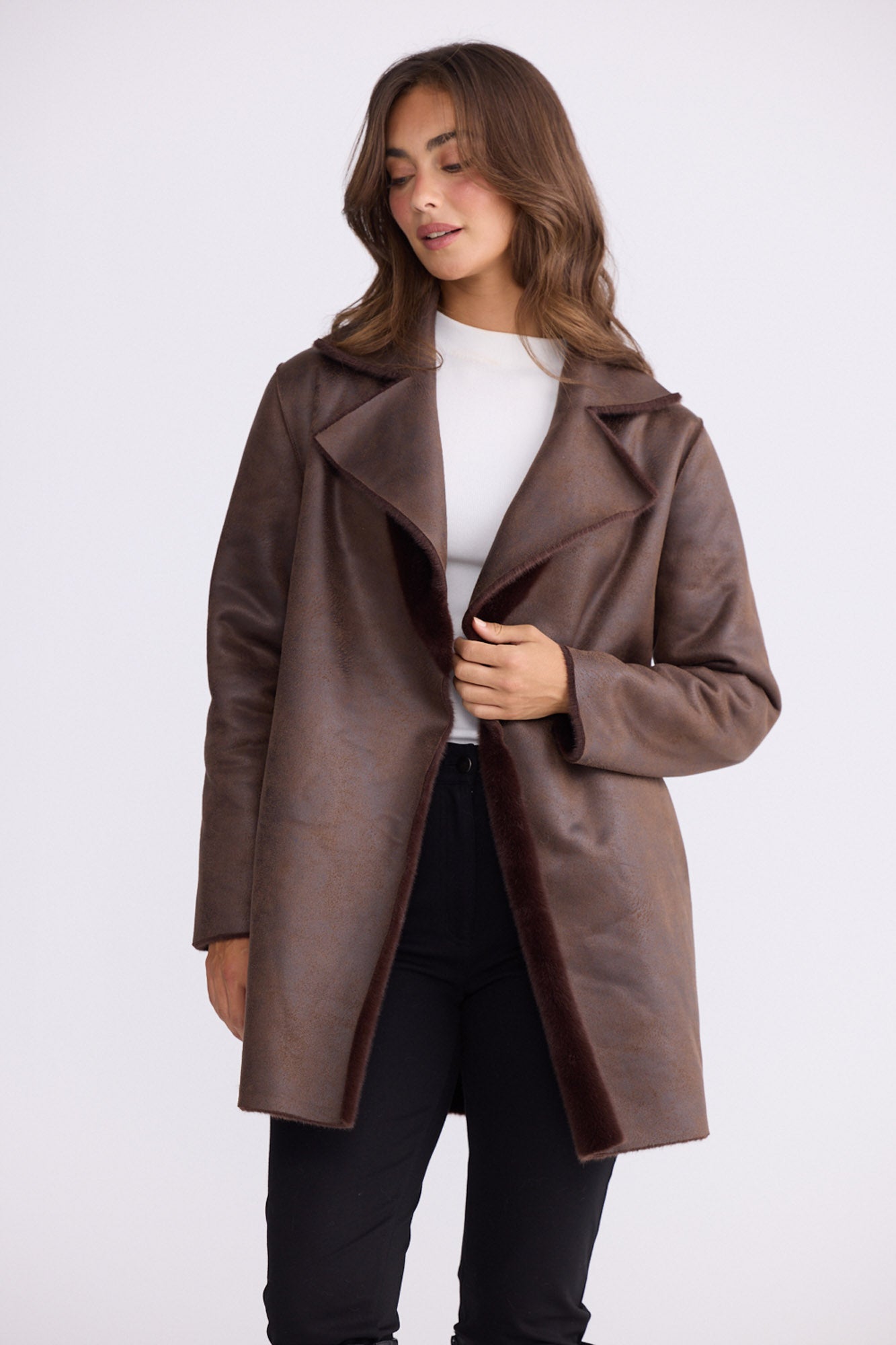Model wearing Odette Fur Coat in brown with notched lapels and long sleeves, back view on white background