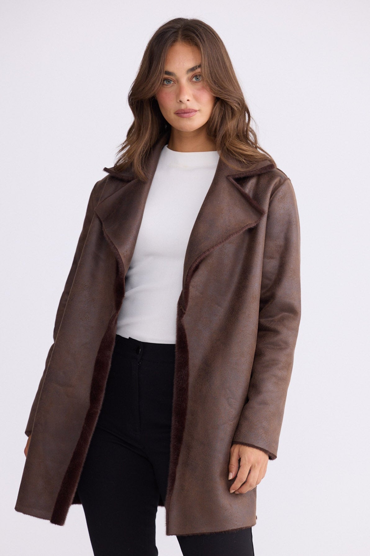 Model wearing Odette Fur Coat in brown with notched lapels and long sleeves, front view on white background