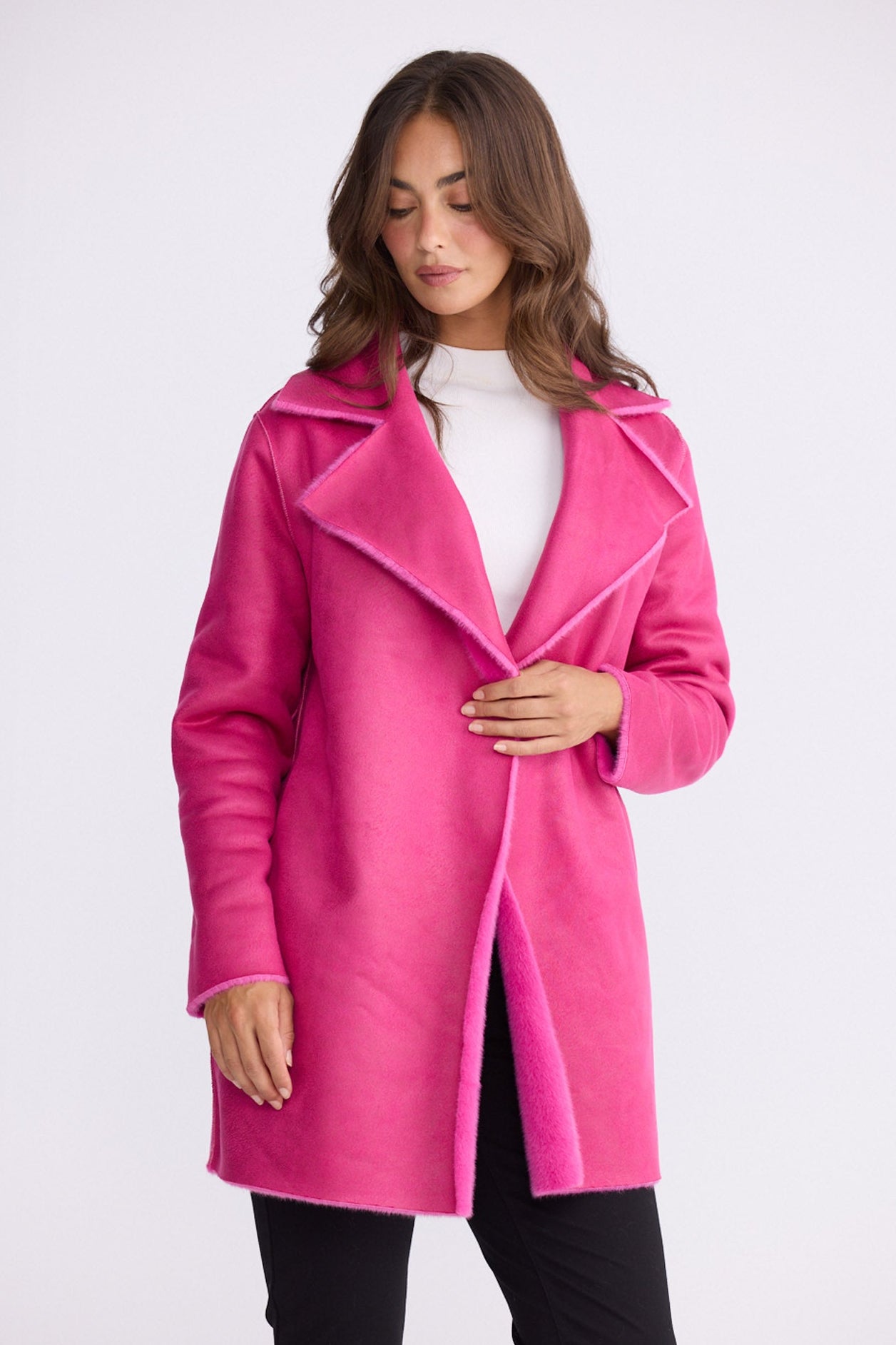 Model wearing Odette Fur Coat in pink with notched lapels and long sleeves, front view on white background