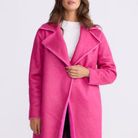 Model wearing Odette Fur Coat in pink with notched lapels and long sleeves, front view on white background