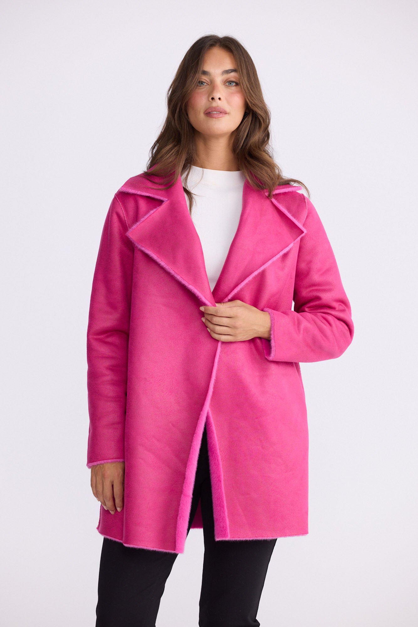 Model wearing Odette Fur Coat in pink with notched lapels and long sleeves, front view on white background