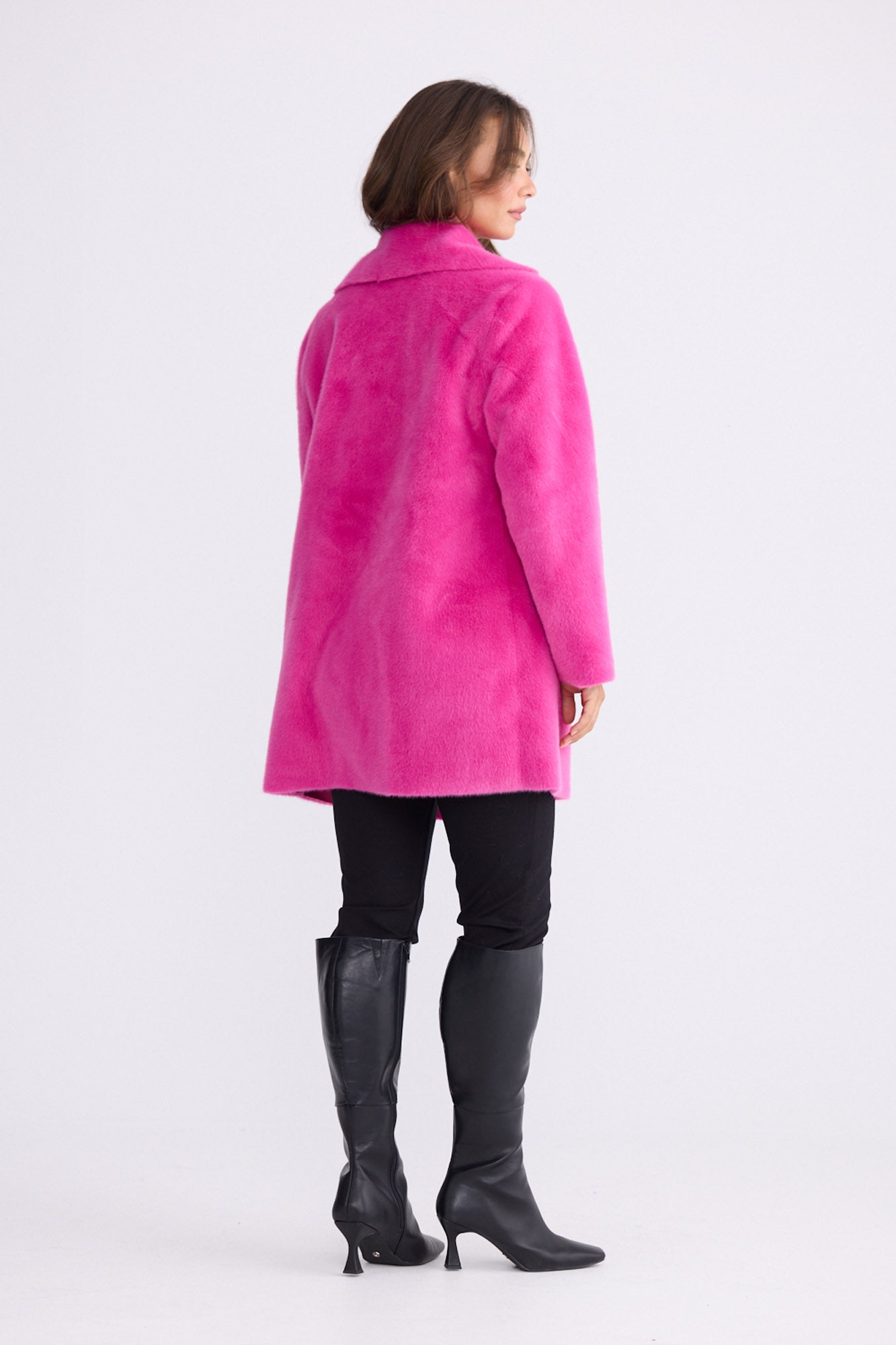 Model wearing Odette Fur Coat in pink with notched lapels and long sleeves, side view on white background