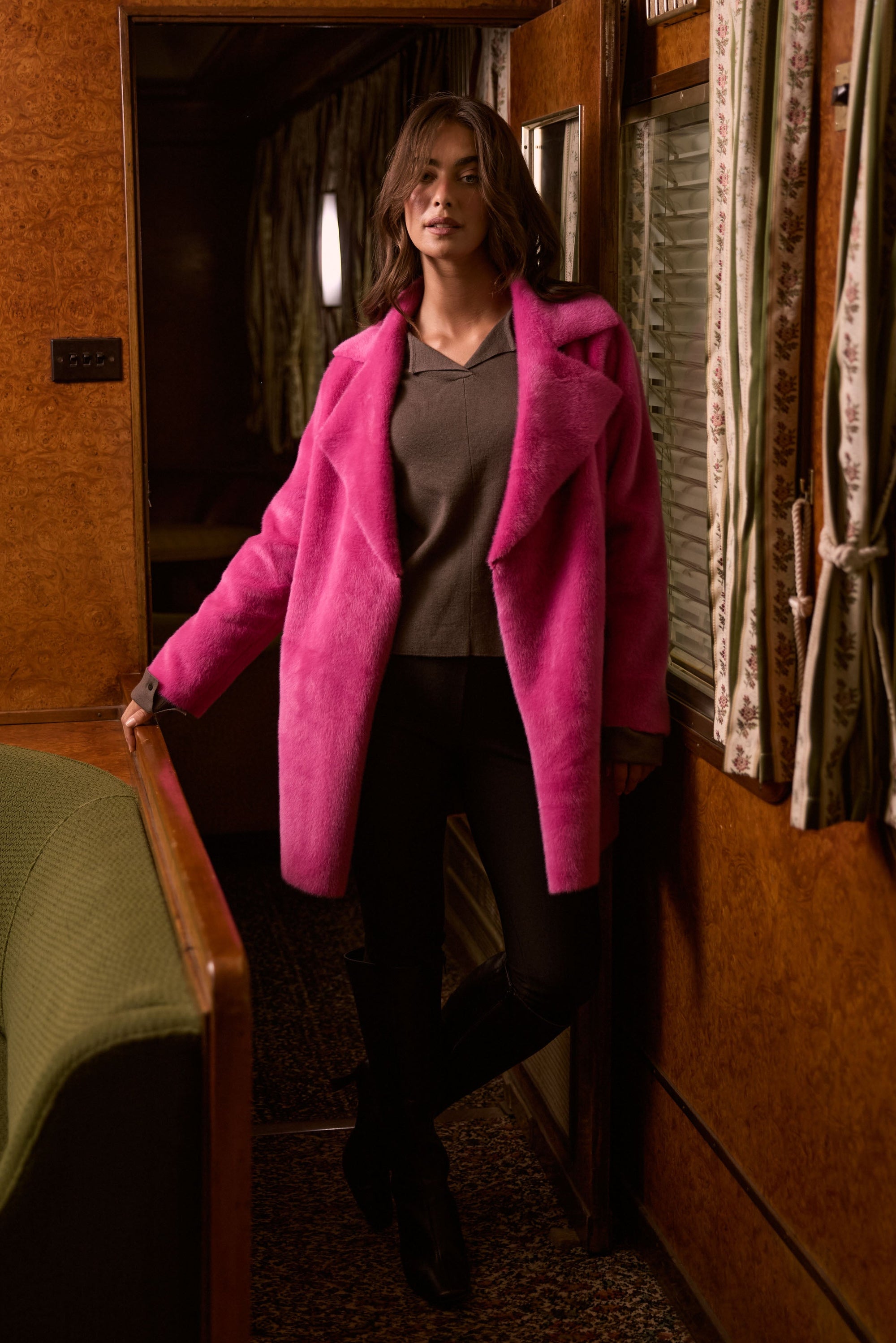 Model wearing Odette Fur Coat in pink with notched lapels and long sleeves, detail view on white background