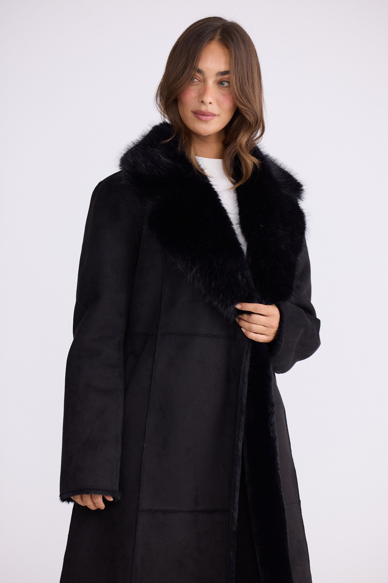 Model wearing Rosamund Fur Coat in black with notched lapels and waist tie, back view on white background