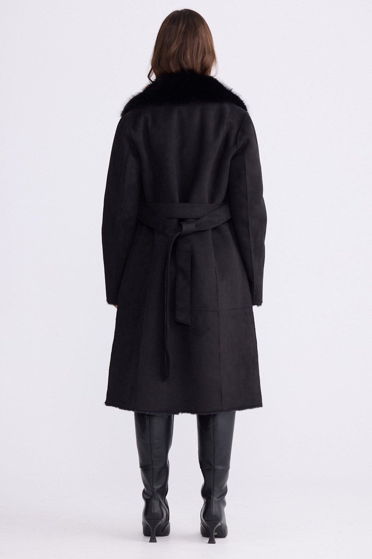 Model wearing Rosamund Fur Coat in black with notched lapels and waist tie, front view on white background