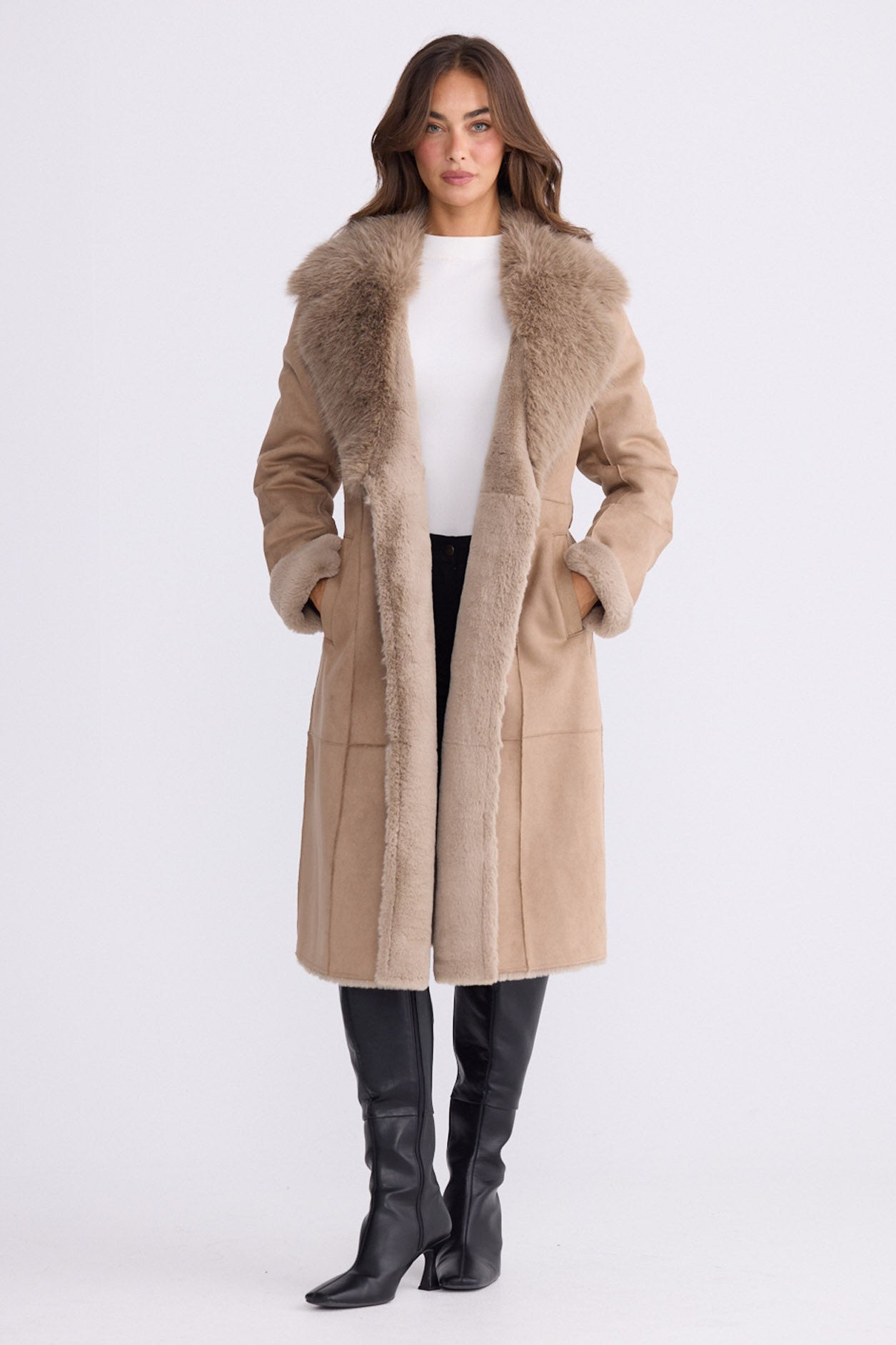 Model wearing Rosamund Fur Coat in beige with notched lapels and waist tie, front view on white background