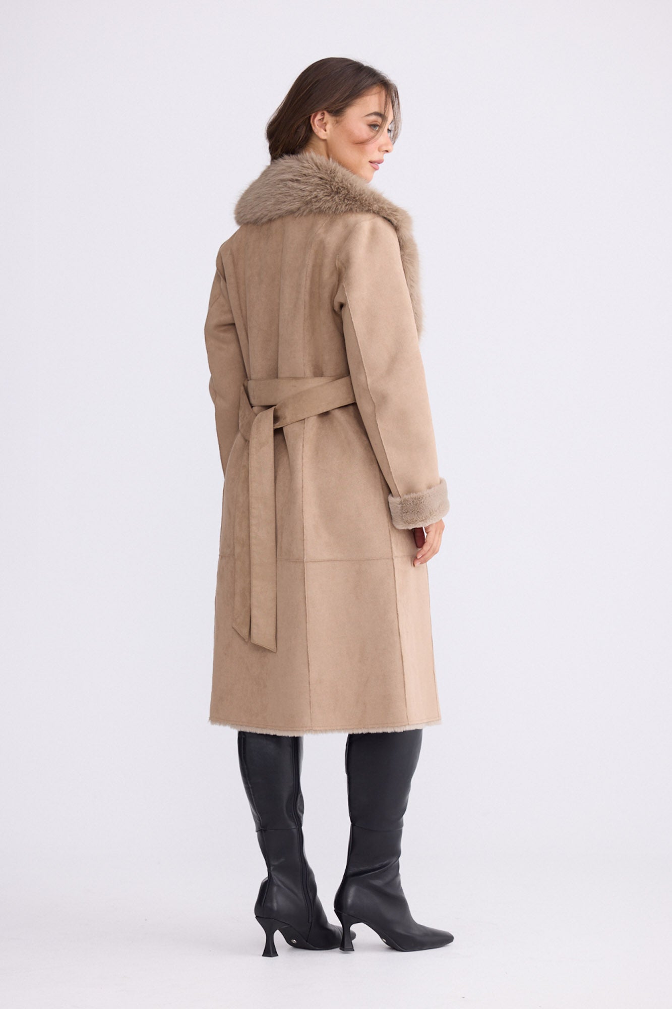 Model wearing Rosamund Fur Coat in beige with notched lapels and waist tie, front view on white background