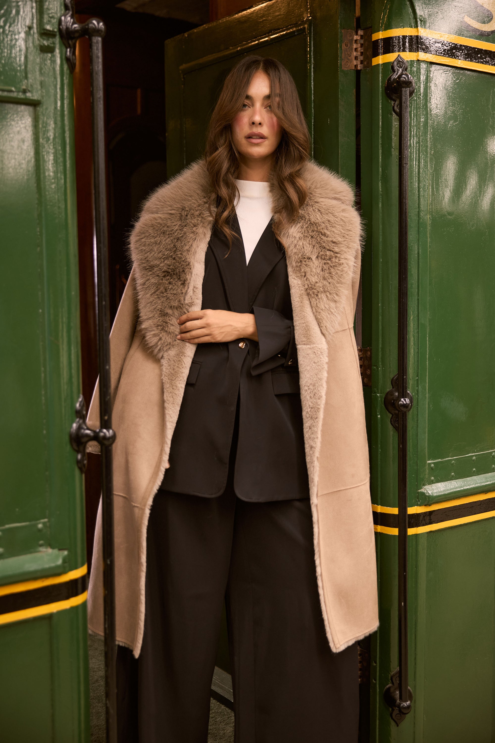 Model wearing Rosamund Fur Coat in beige with notched lapels and waist tie, detail view on white background
