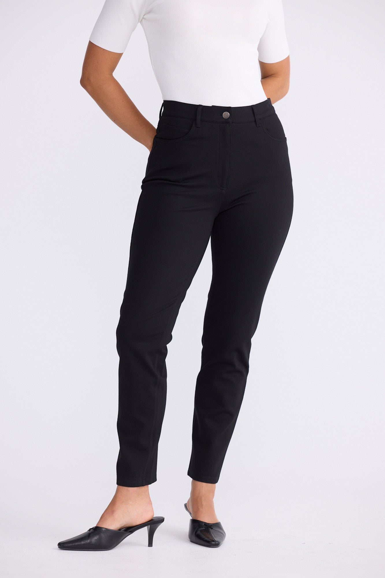 Model wearing Aero Pant black pants with back patch pockets, alternate studio view on white background