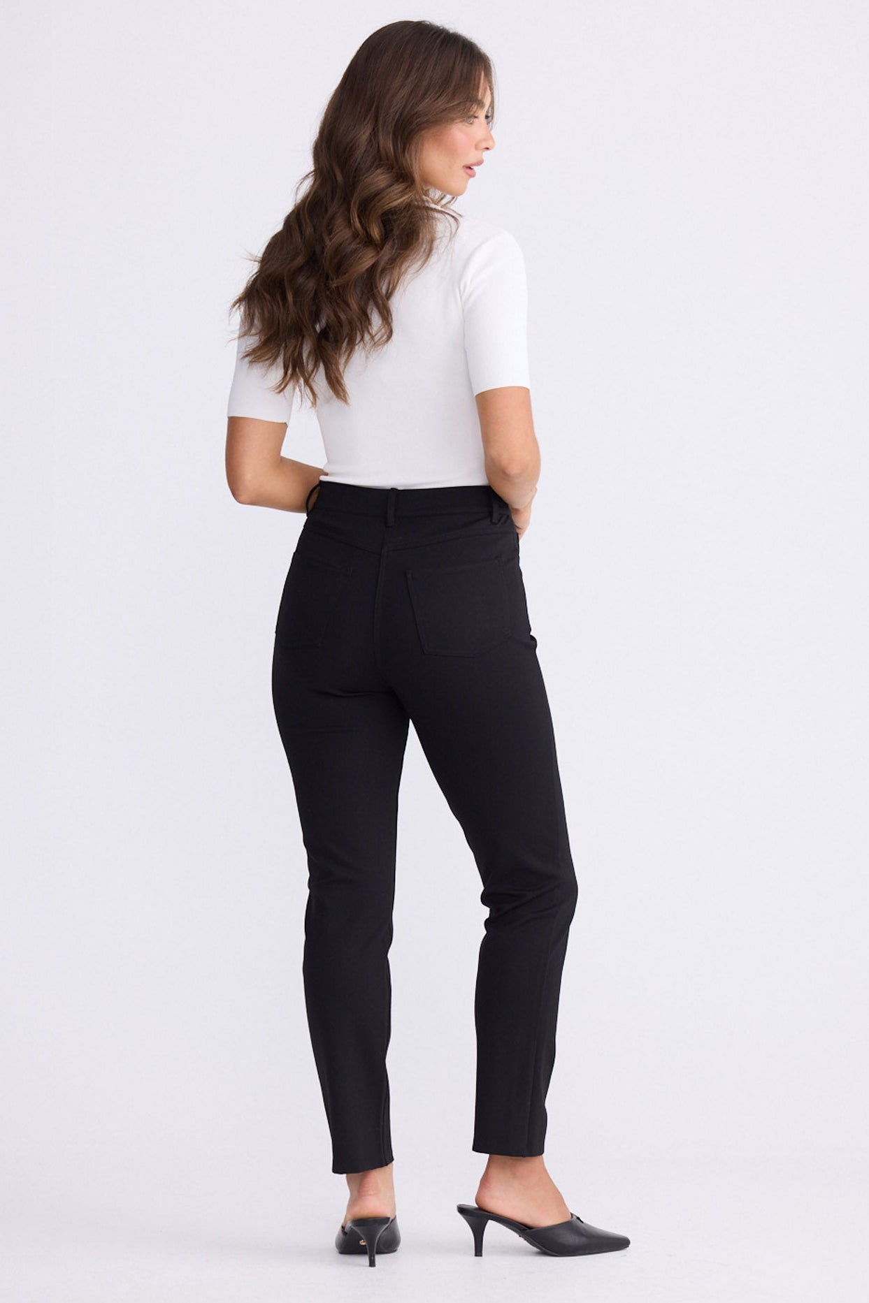 Model wearing Aero Pant black pants with back patch pockets, alternate studio view on white background