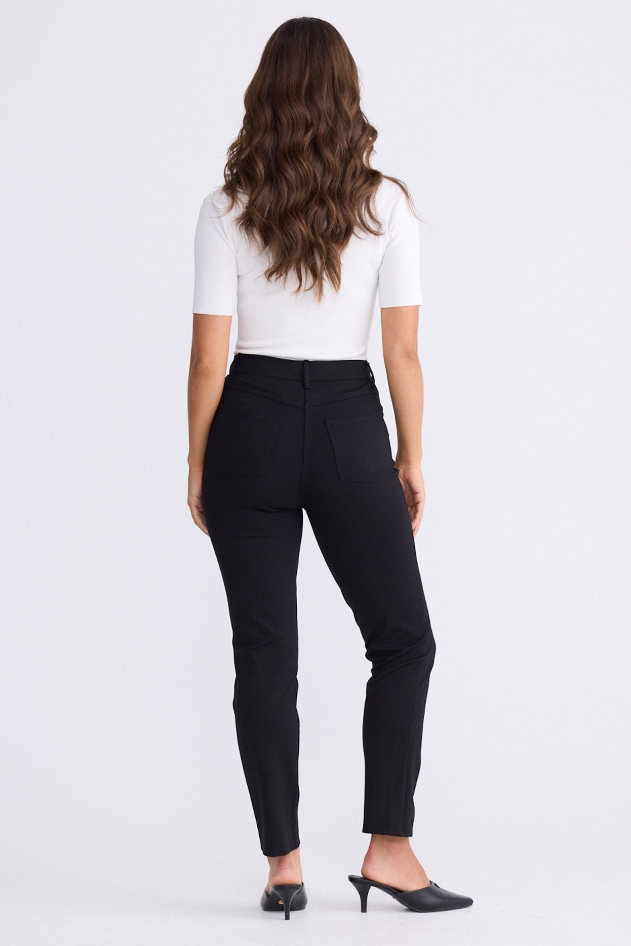 Model wearing Aero Pant black pants with back patch pockets, alternate studio view on white background