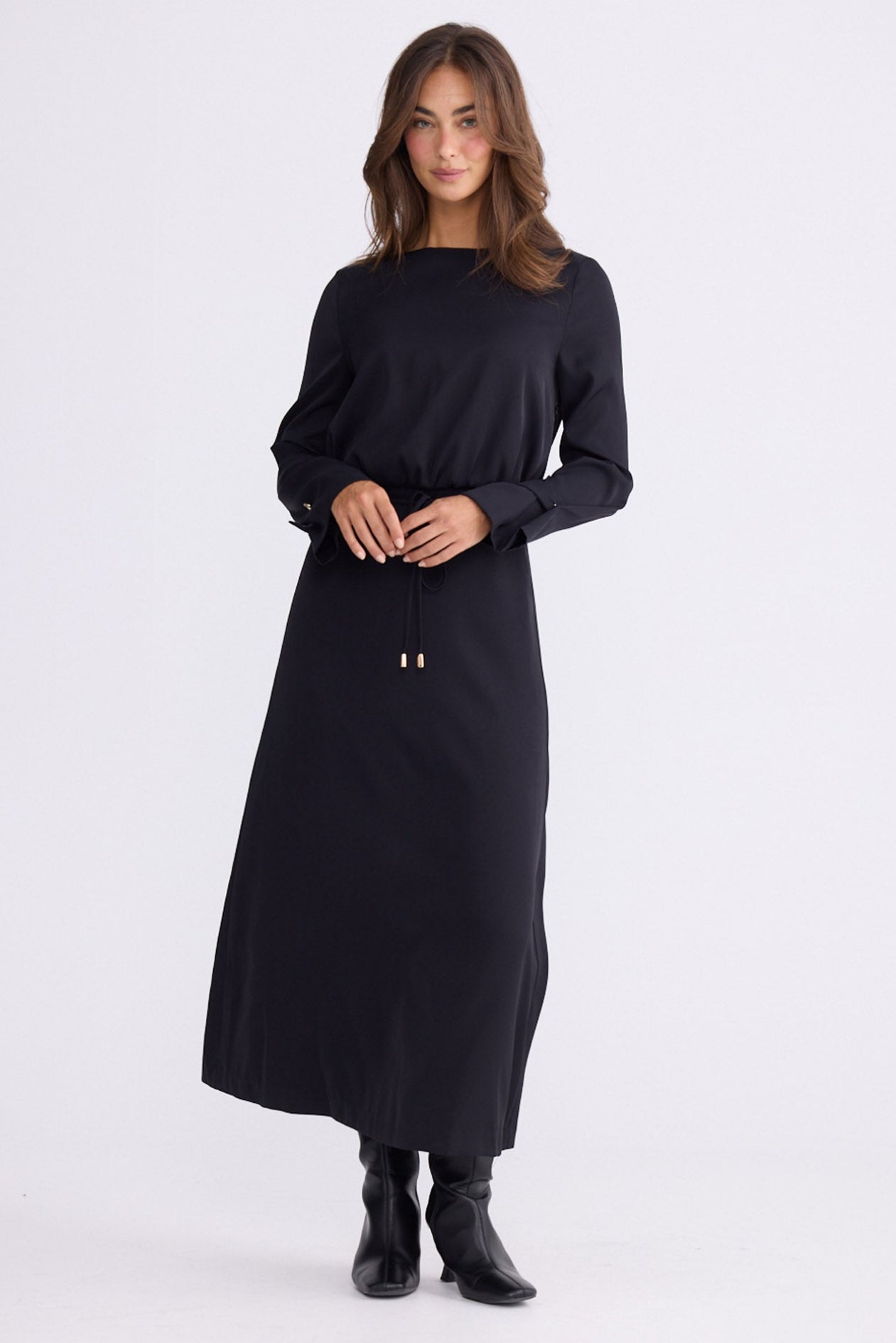 Model wearing Kensington Dress in black with boat neckline and long sleeves, back view on white background