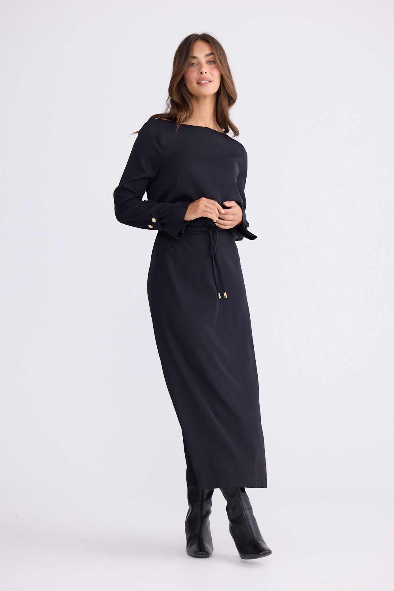 Model wearing Kensington Dress in black with boat neckline and long sleeves, front view on white background