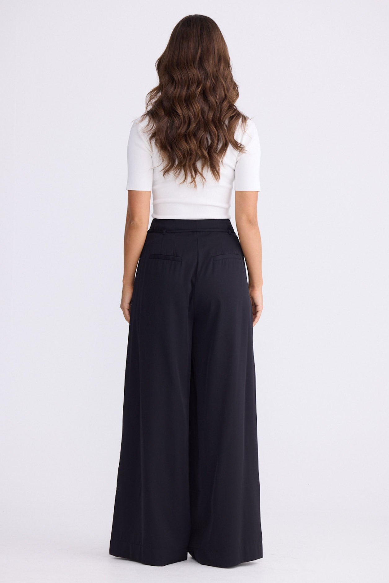 Model wearing Kensington Pant in black with waist tie and wide-leg shape, front view on white background