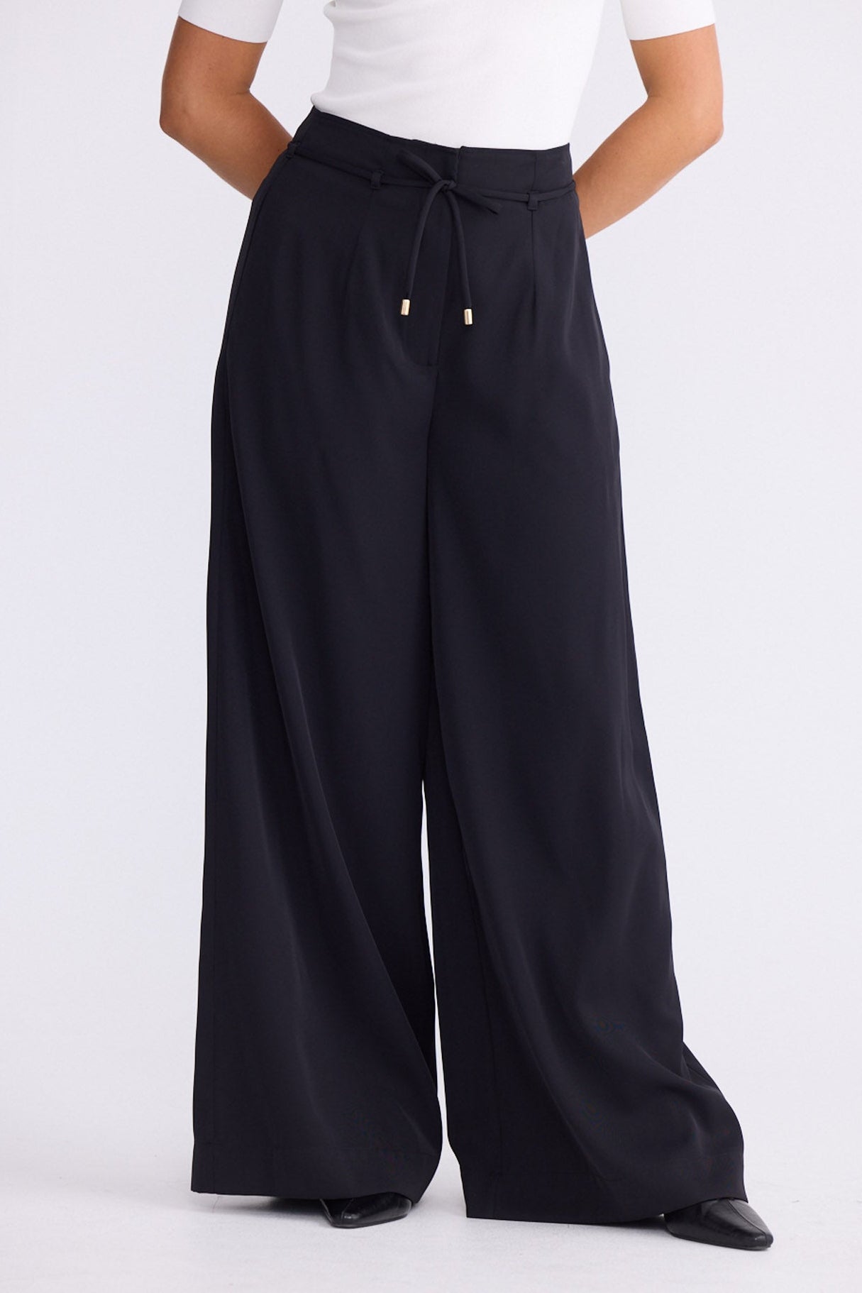 Model wearing Kensington Pant in black with waist tie and wide-leg shape, front view on white background