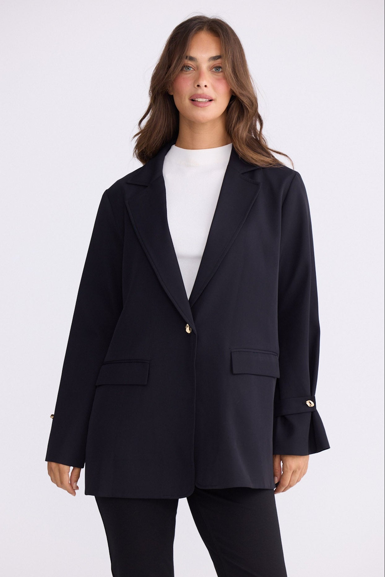 Model wearing Kensington Blazer in black with notched lapels and long sleeves, front view on white background
