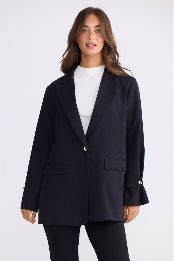 Model wearing Kensington Blazer in black with notched lapels and long sleeves, front view on white background