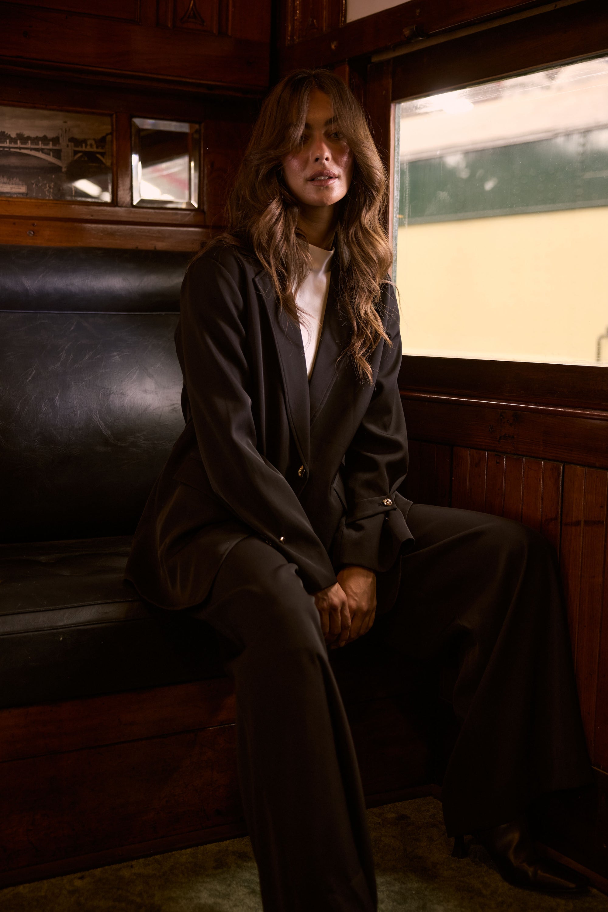 Model wearing Kensington Blazer in black with notched lapels and long sleeves, detail view on white background