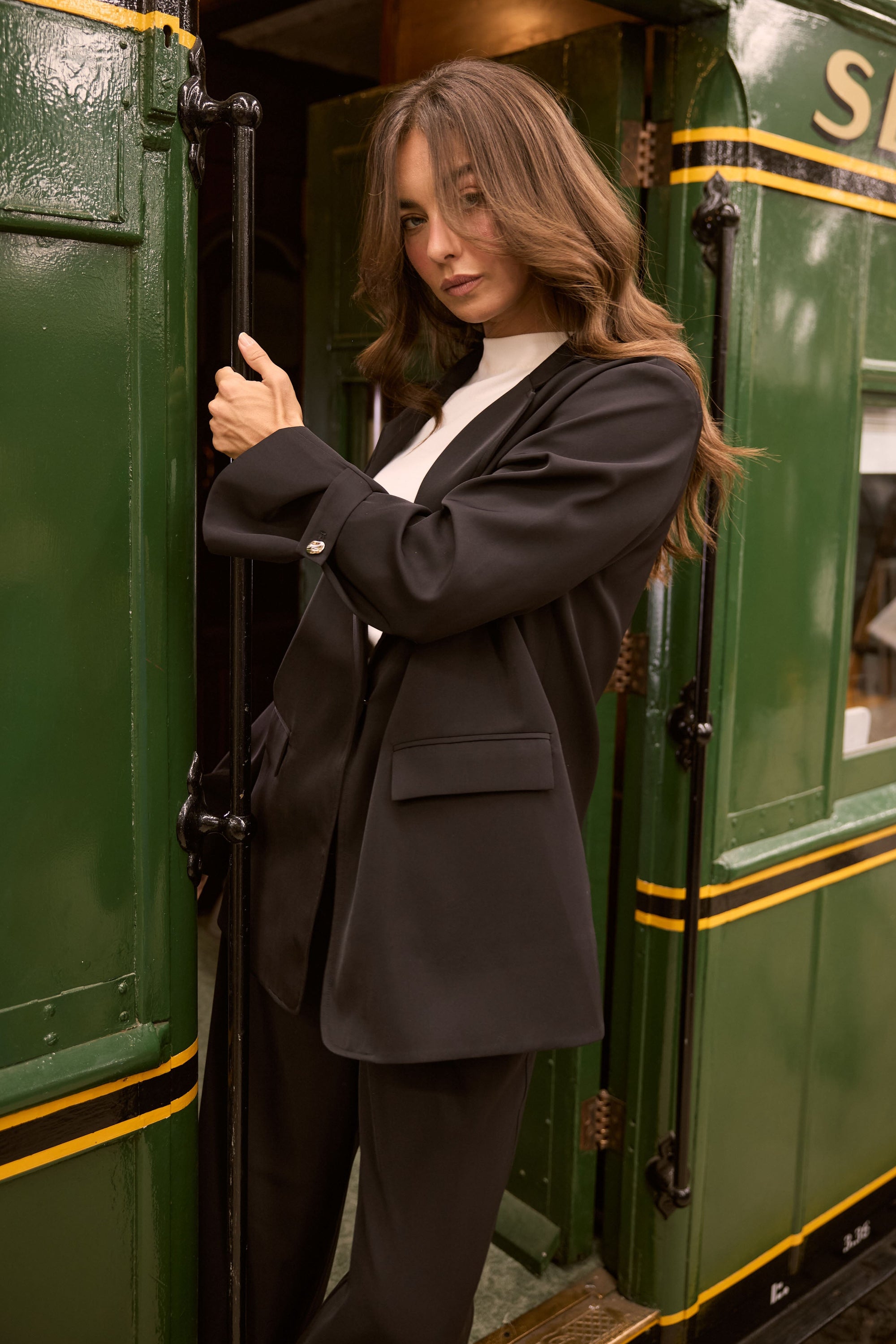 Model wearing Kensington Blazer in black with notched lapels and long sleeves, detail view on white background