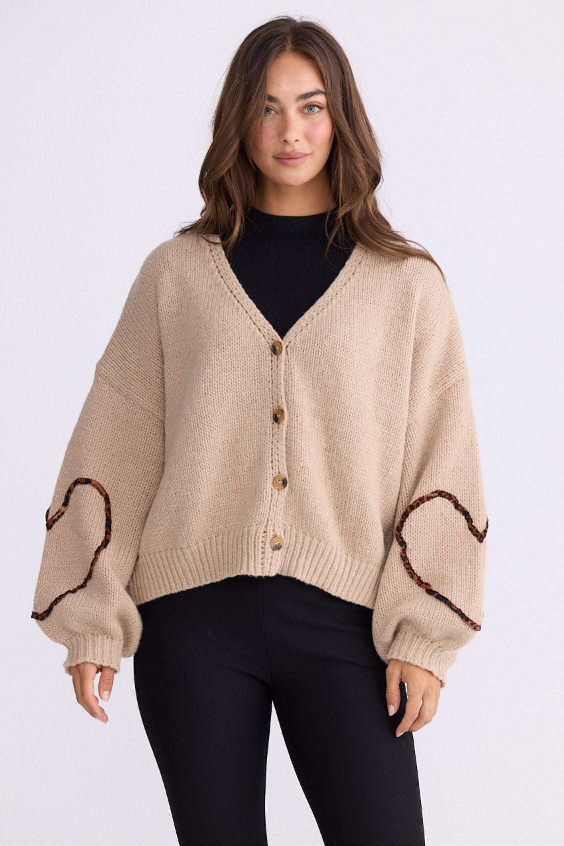 Model wearing Angie Knit Cardi beige cardigan with V-neckline, button-front closure, front view on white background