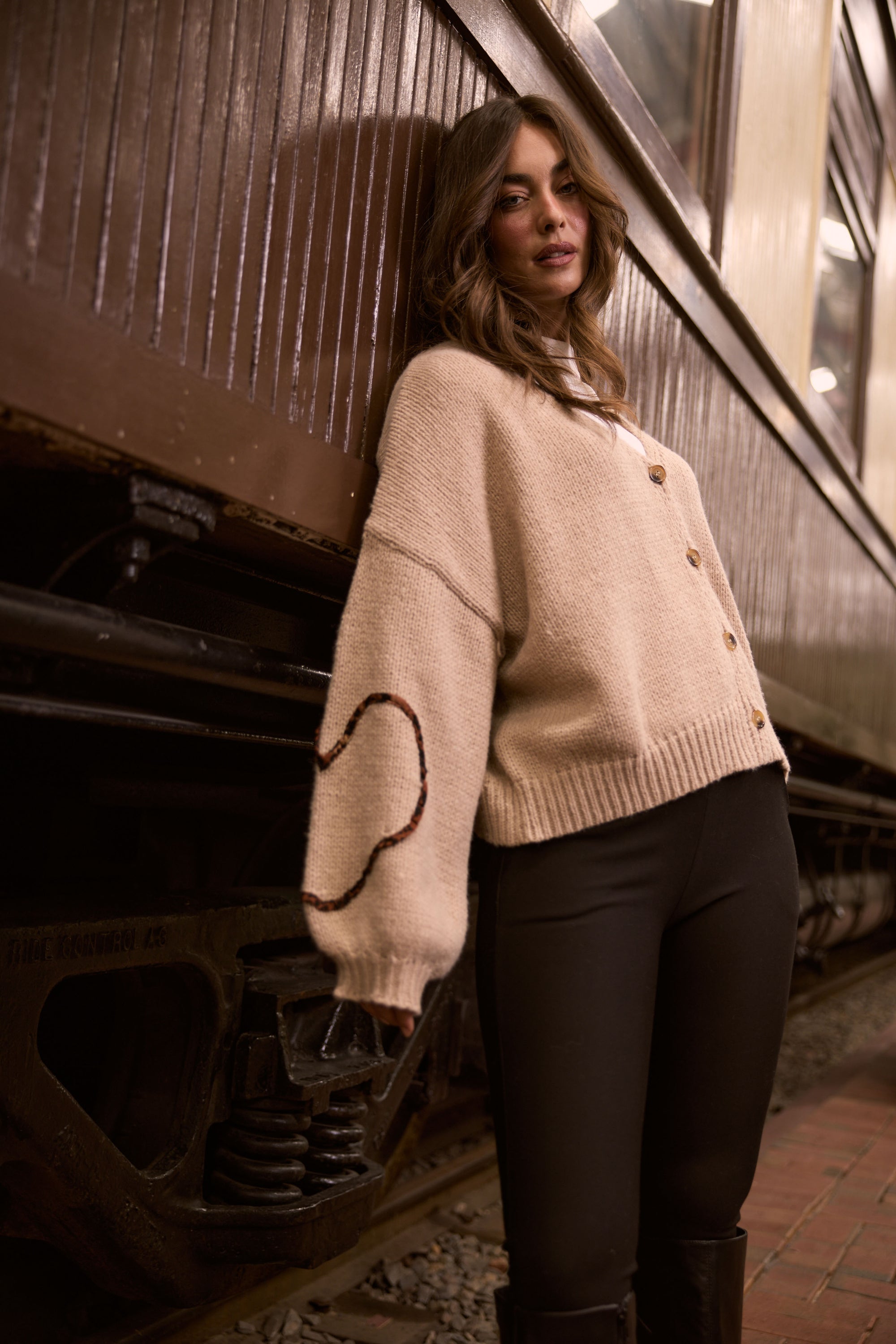 Model wearing Angie Knit Cardi beige cardigan with V-neckline, button-front closure, alternate studio view on white background