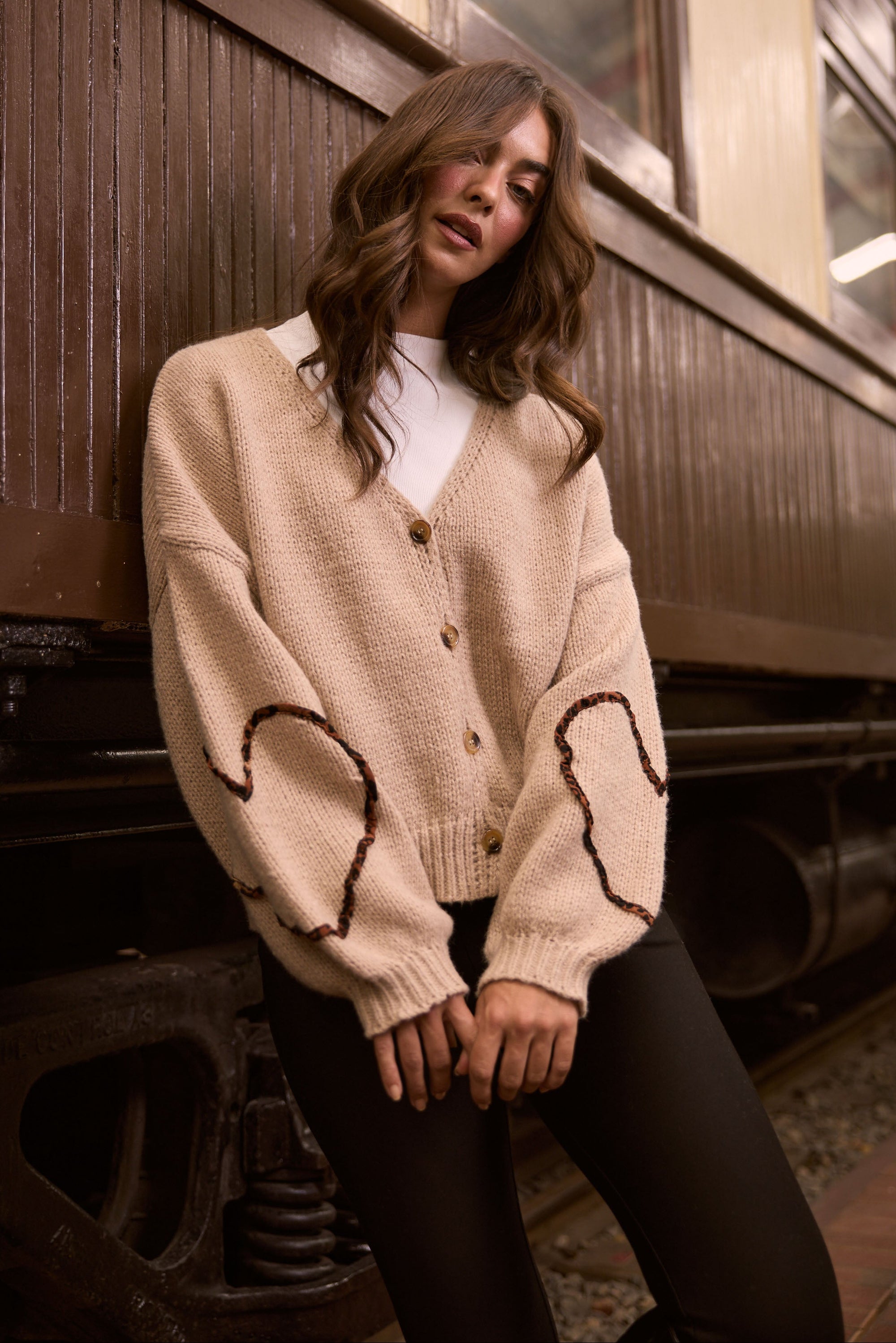 Model wearing Angie Knit Cardi beige cardigan with V-neckline, button-front closure, alternate studio view on white background