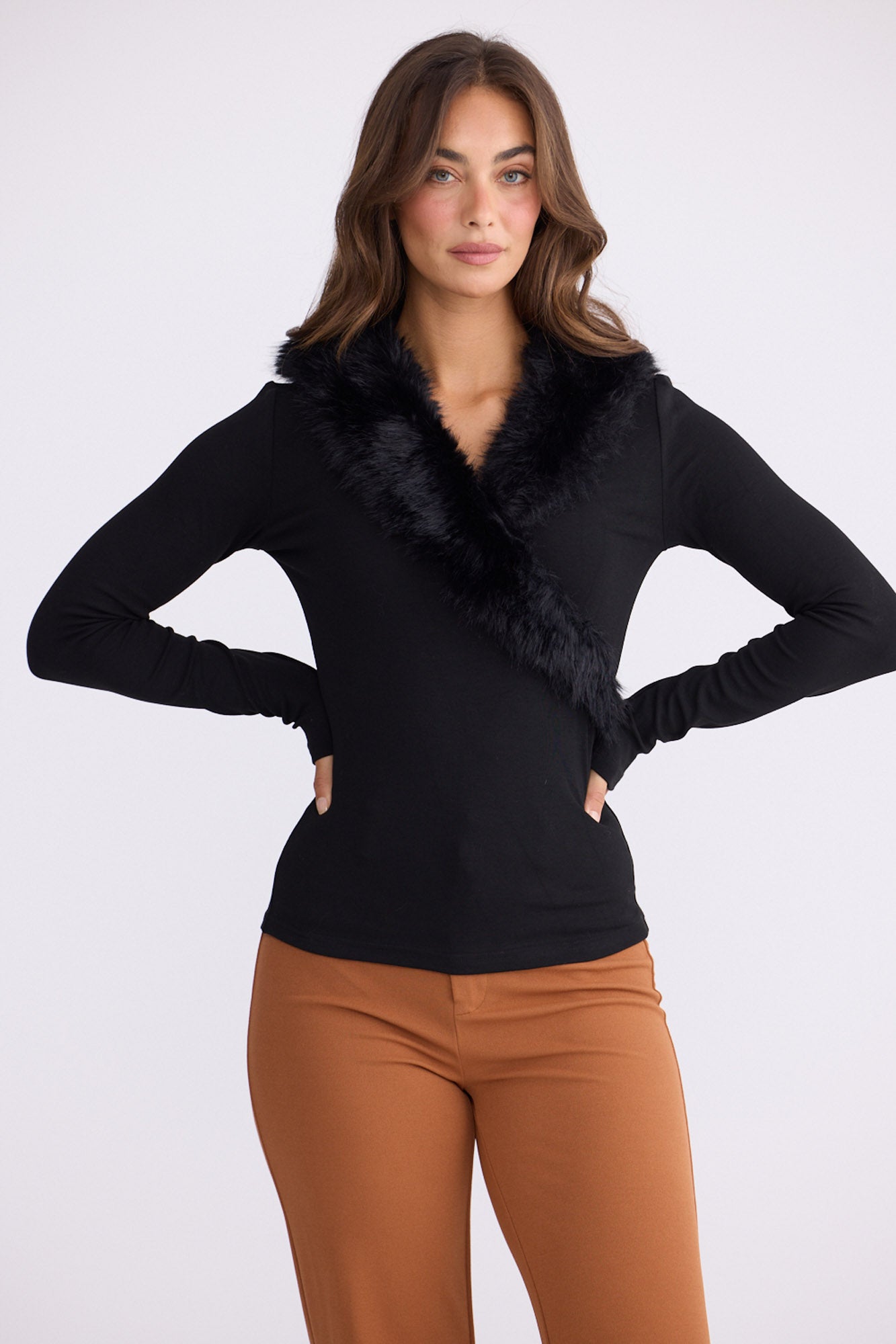 Model wearing Imelda Top in black with V-neck and long sleeves, front view on white background