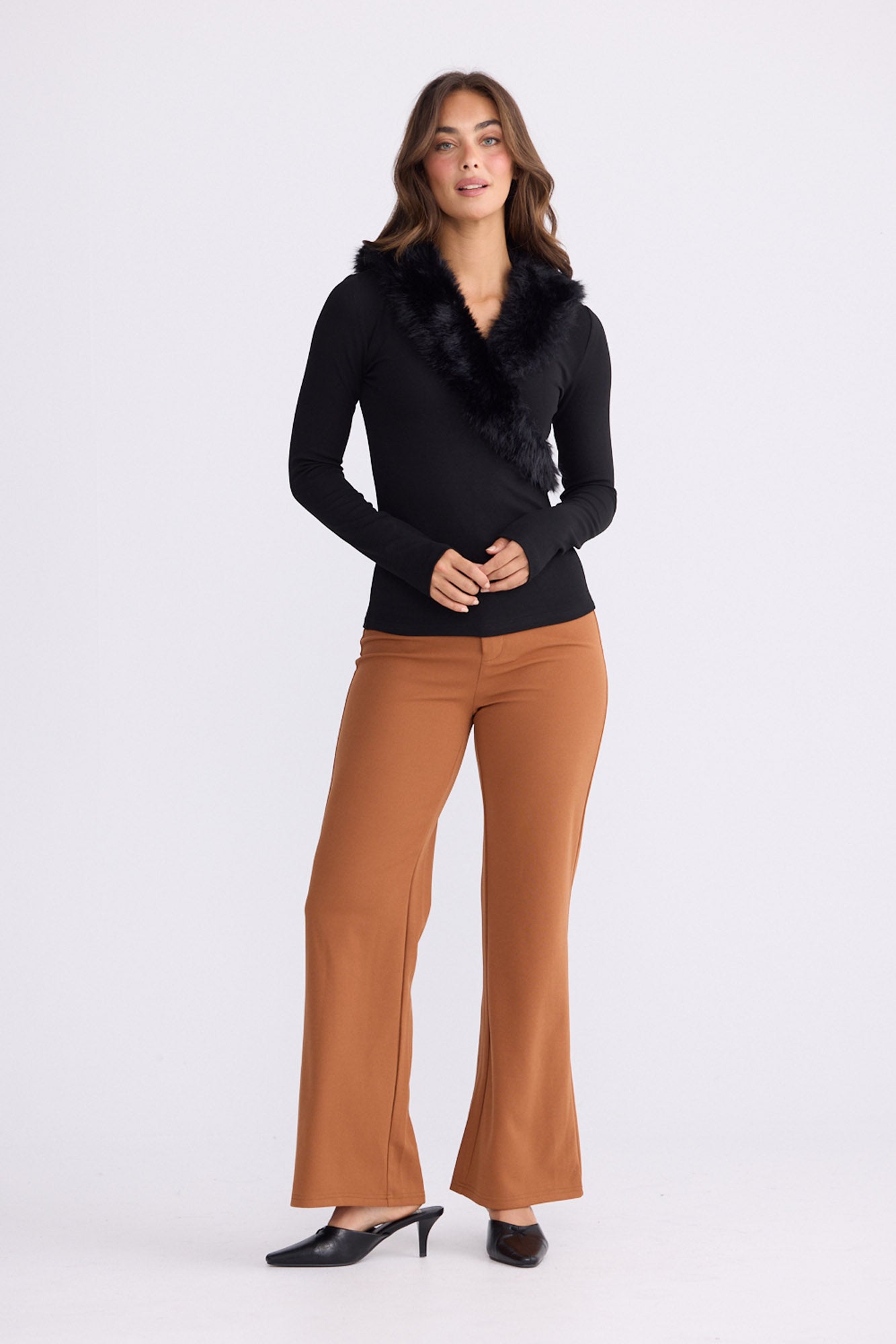 Model wearing Imelda Top in black with V-neck and long sleeves, front view on white background