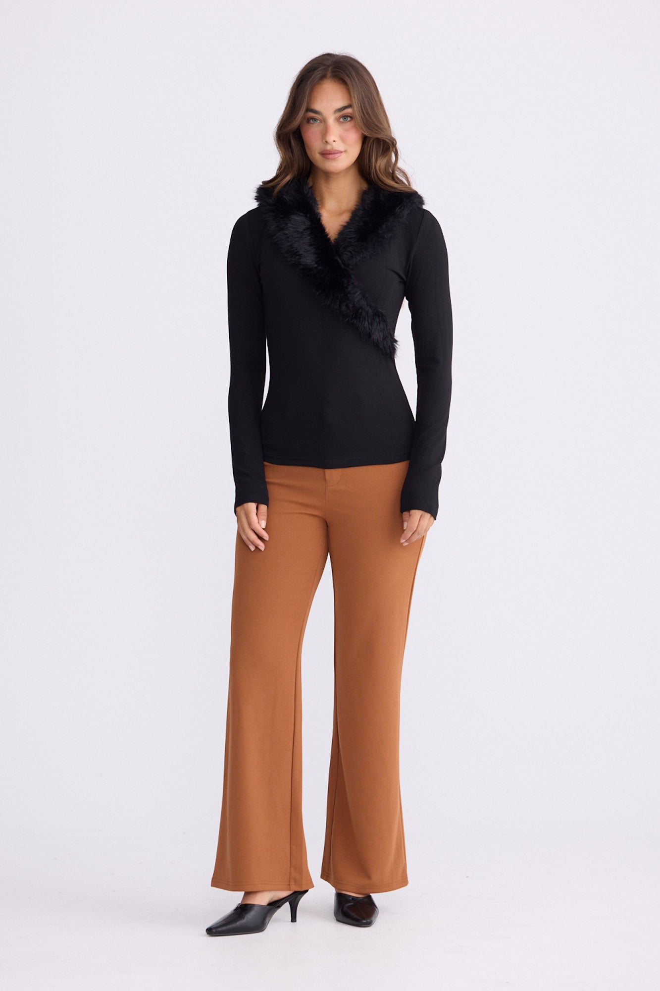 Model wearing Imelda Top in black with V-neck and long sleeves, front view on white background