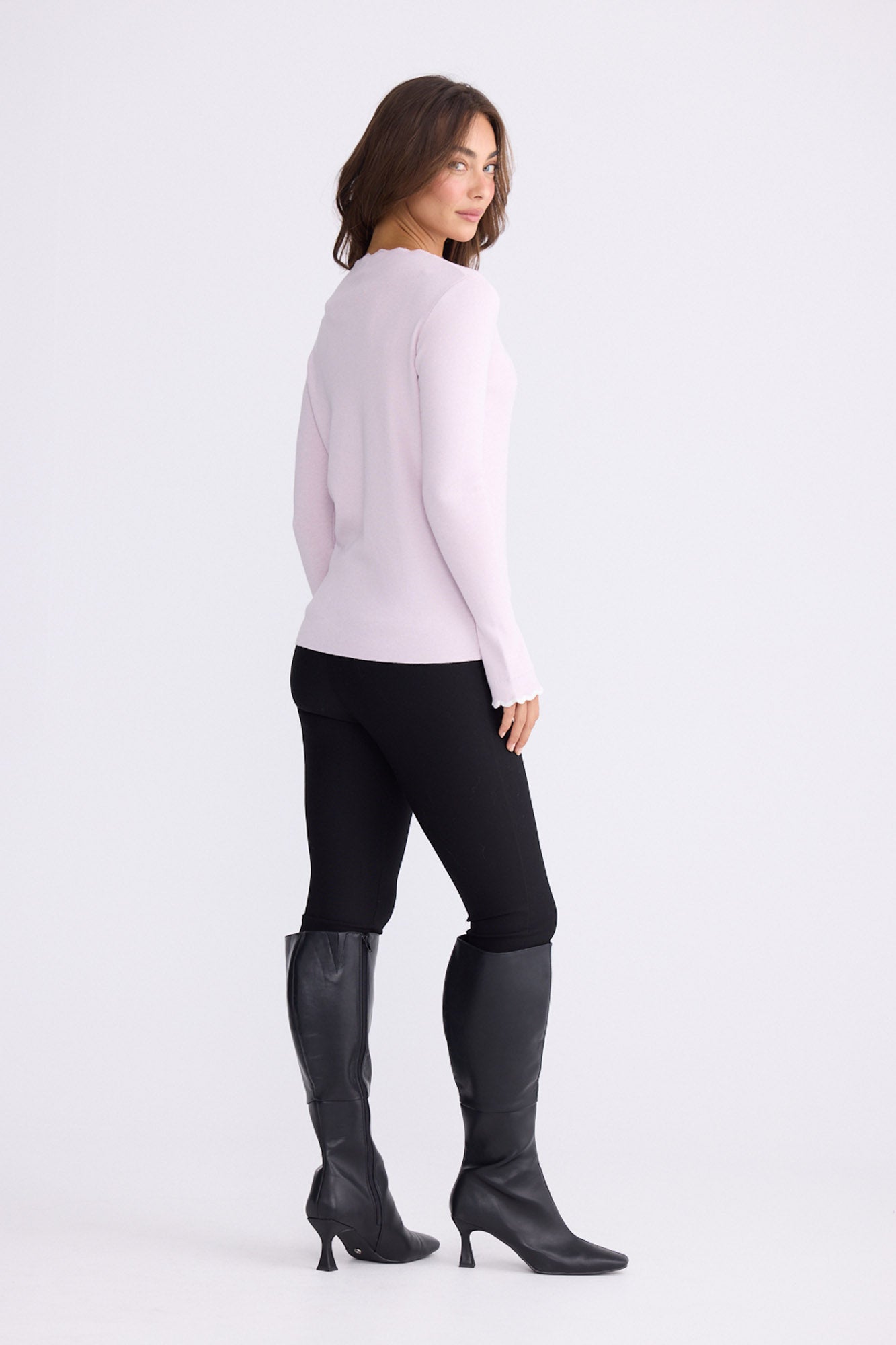 Model wearing Stacey blush knit top with scalloped contrast trim, back view on white background