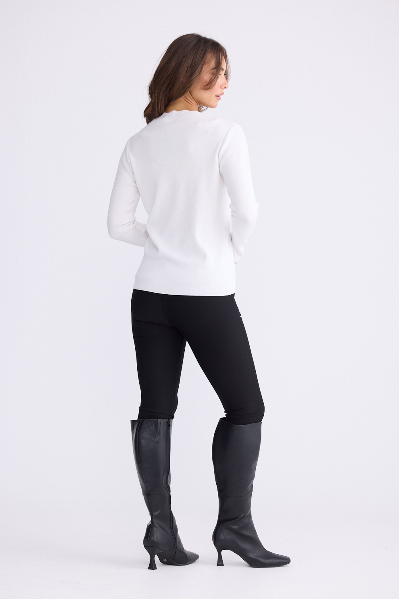 Model wearing Stacey white knit top with scalloped contrast trim, back view on white background