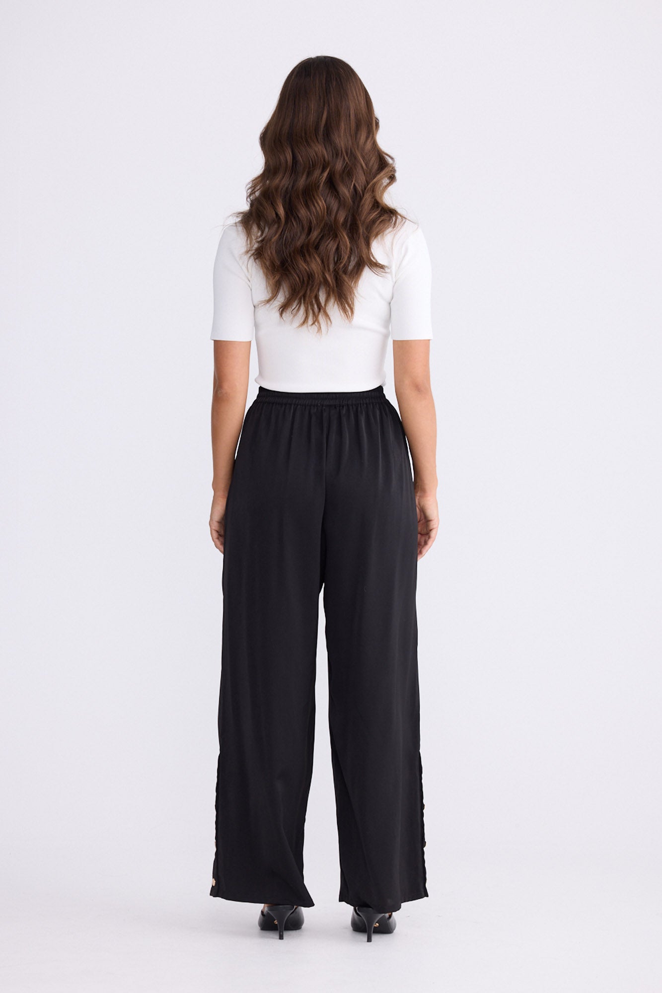 Model wearing Cassian Pant black pants with cutaway hip pockets, alternate studio view on white background