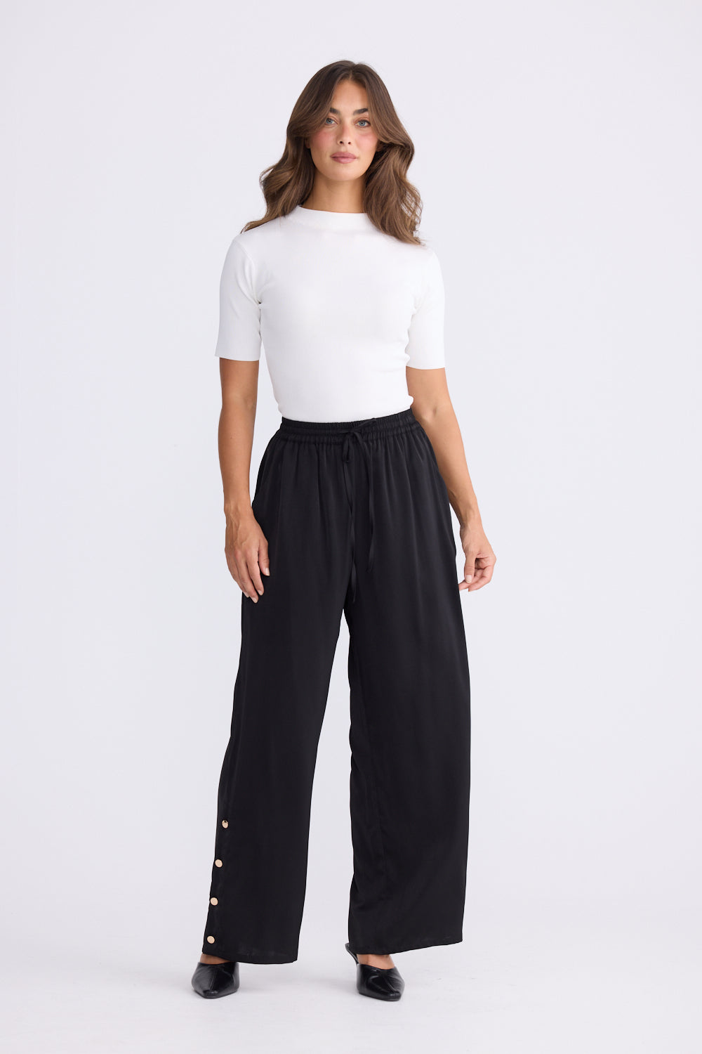 Woman wearing a white top and black wide-leg pants on a white background
