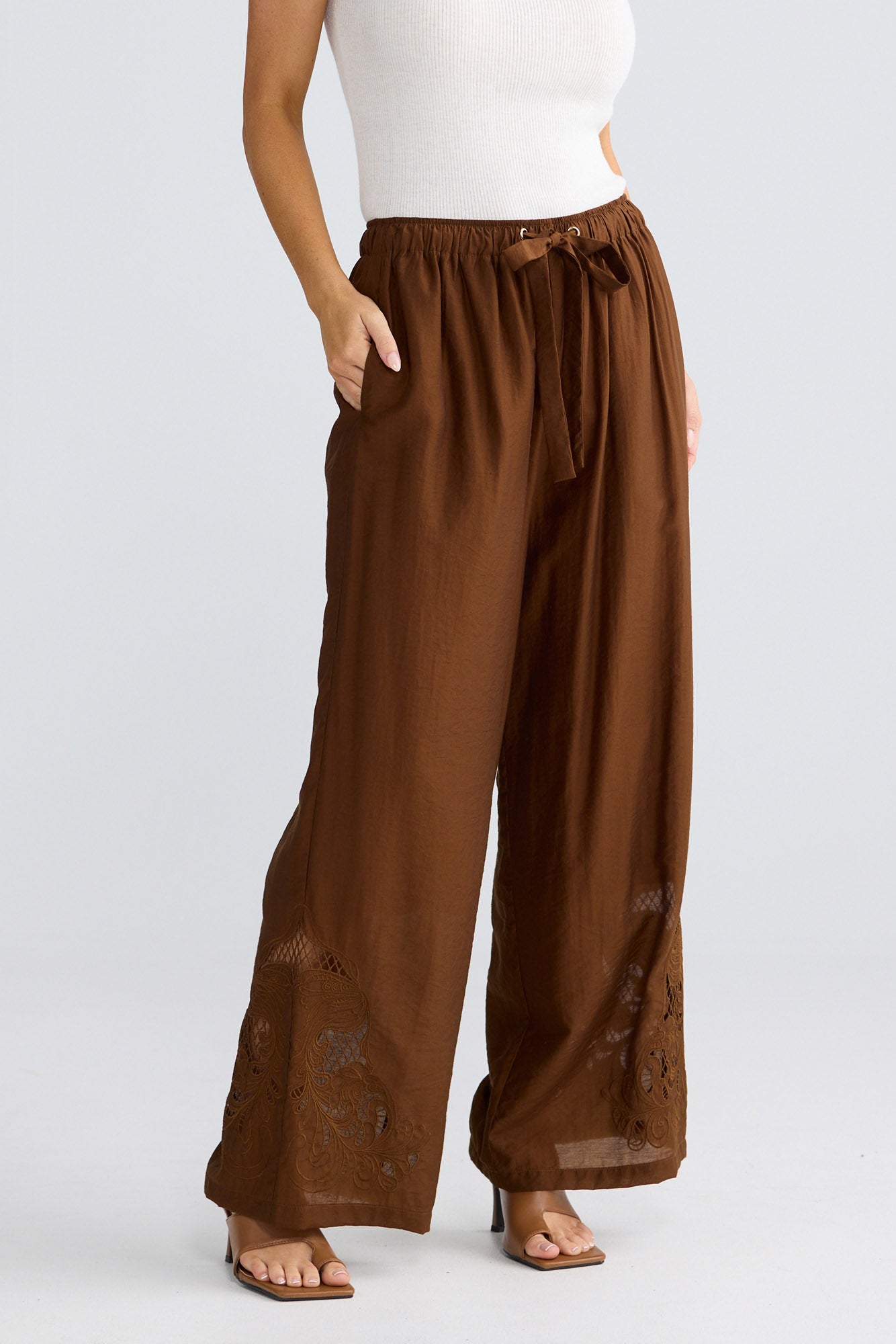 Model wearing Astrid Pant in bronze by Brave + True, front view showing wide-leg silhouette.