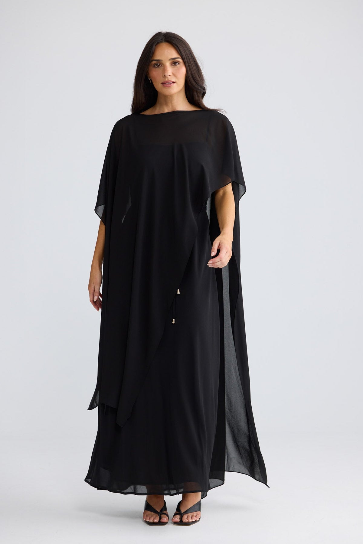 Model wearing Park Avenue Cape in black by Brave + True, front view showing draped silhouette.
