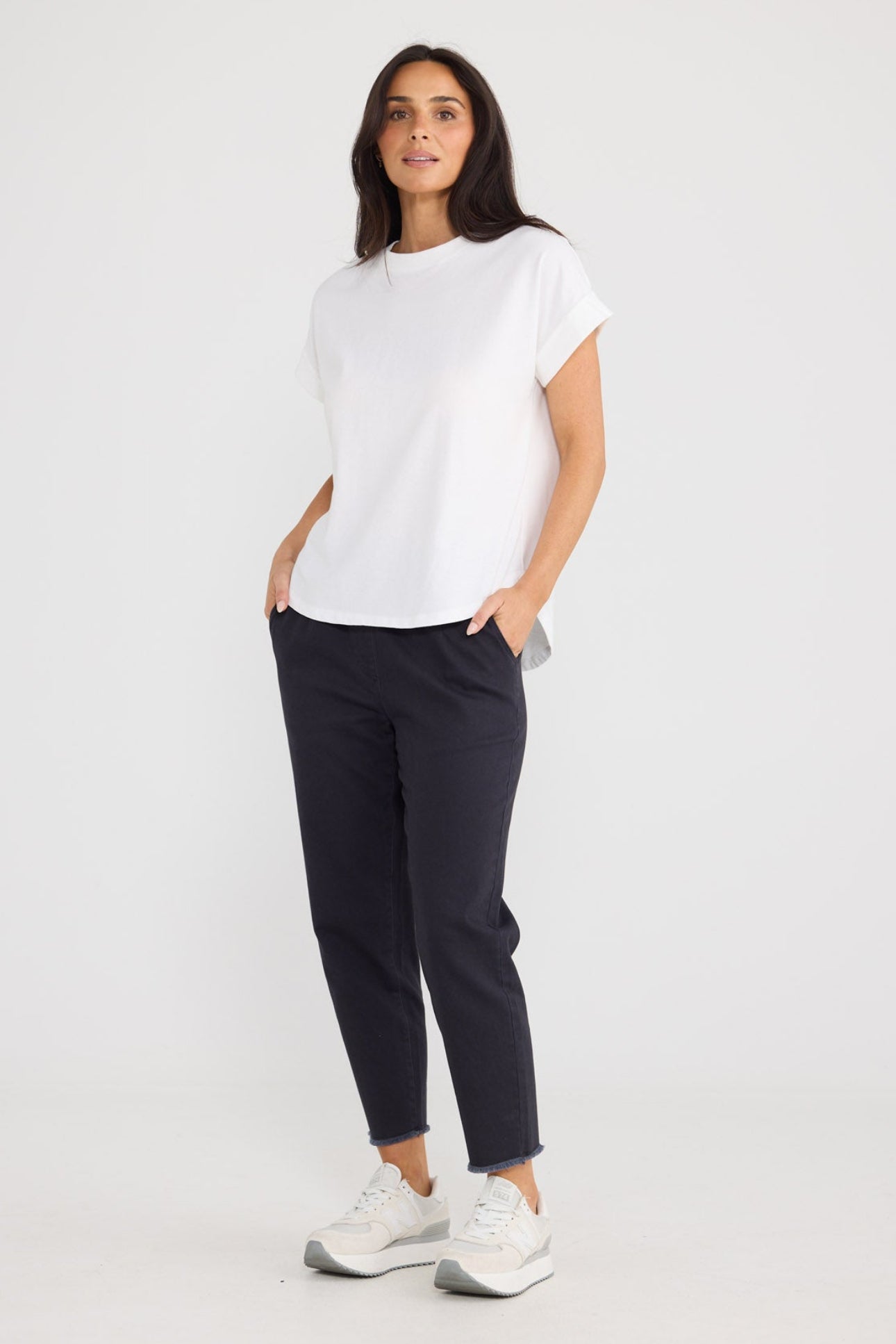 Model wearing Sandra Tee in white by Brave + True, front view with curved hem.