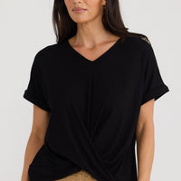 Model wearing Rapture Tee in black by Brave + True, front view with twist front.
