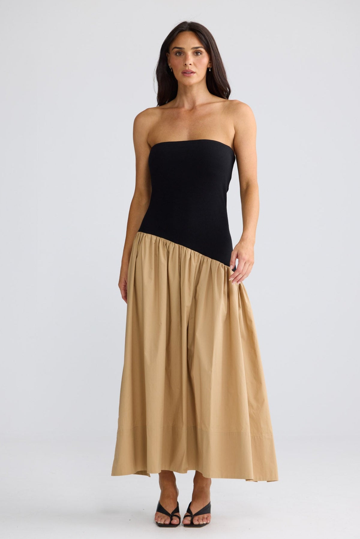 Model wearing Sonita Dress with black bodice and beige skirt by Brave + True, front view.