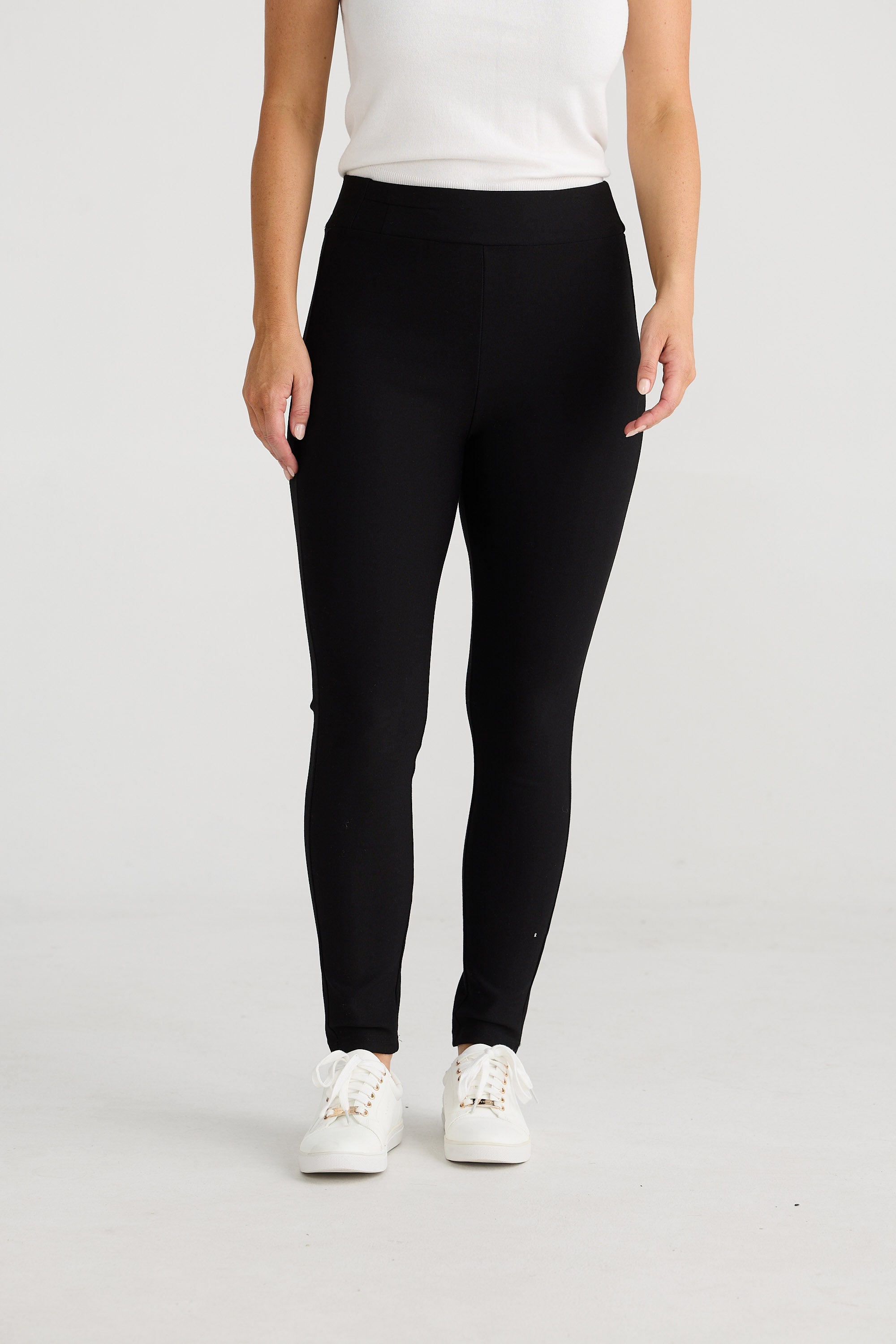 Person wearing black leggings and white sneakers on a light gray background