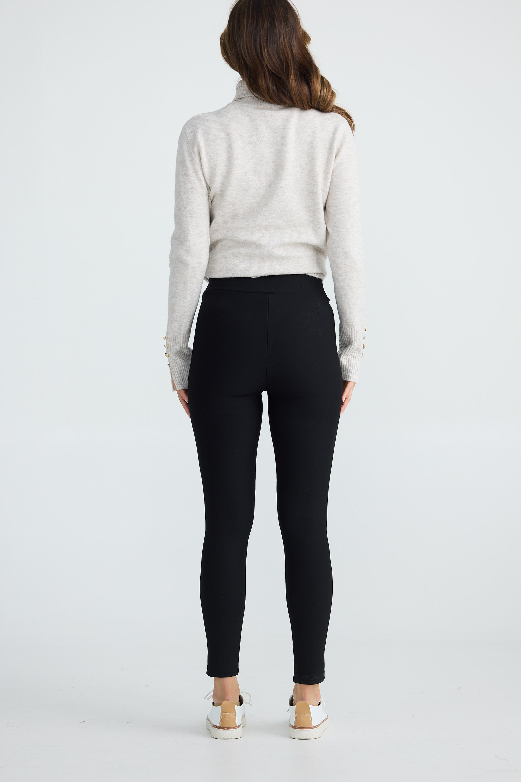 Person wearing a white sweater and black pants on a white background