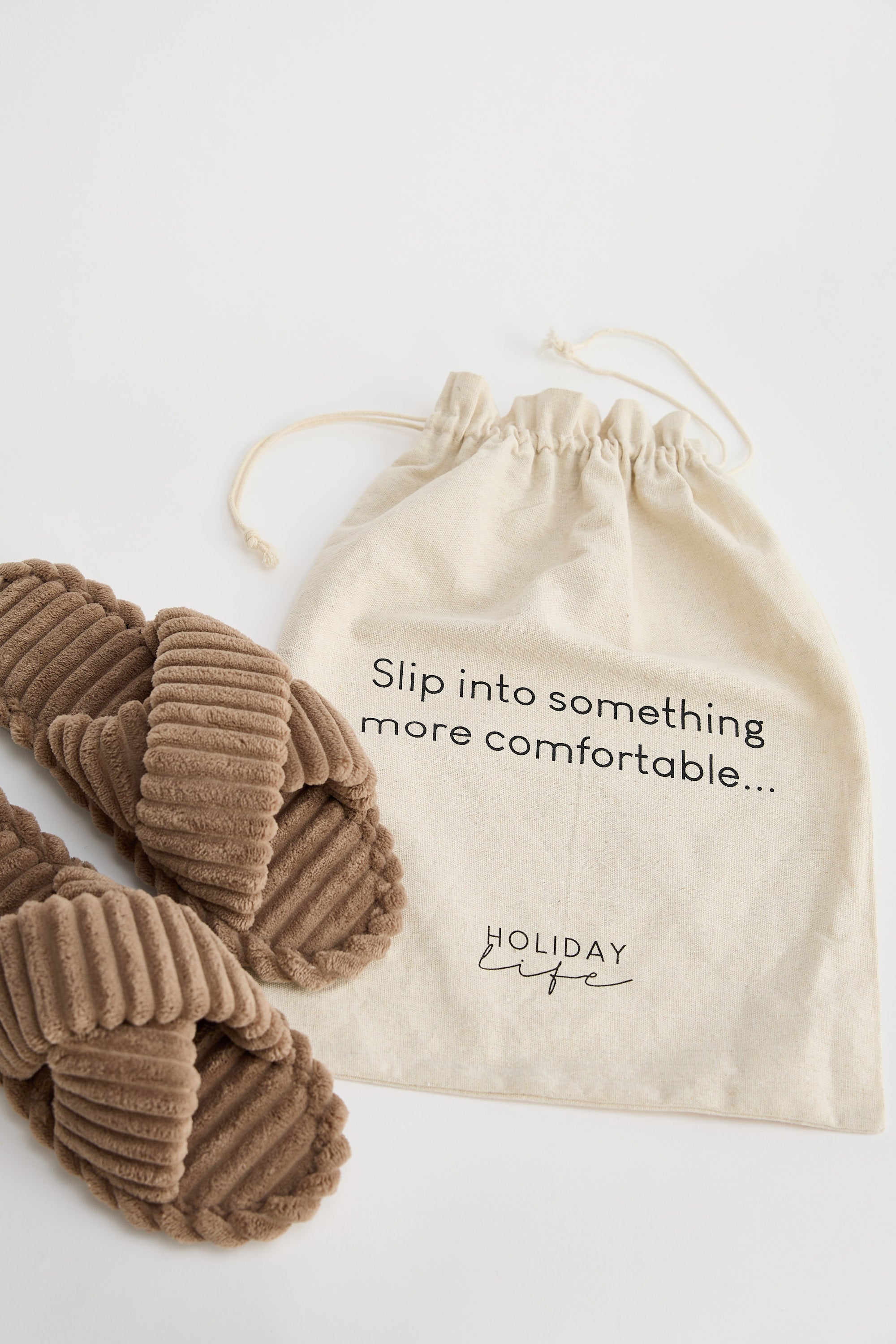Pair of brown slippers with a drawstring bag on a white background