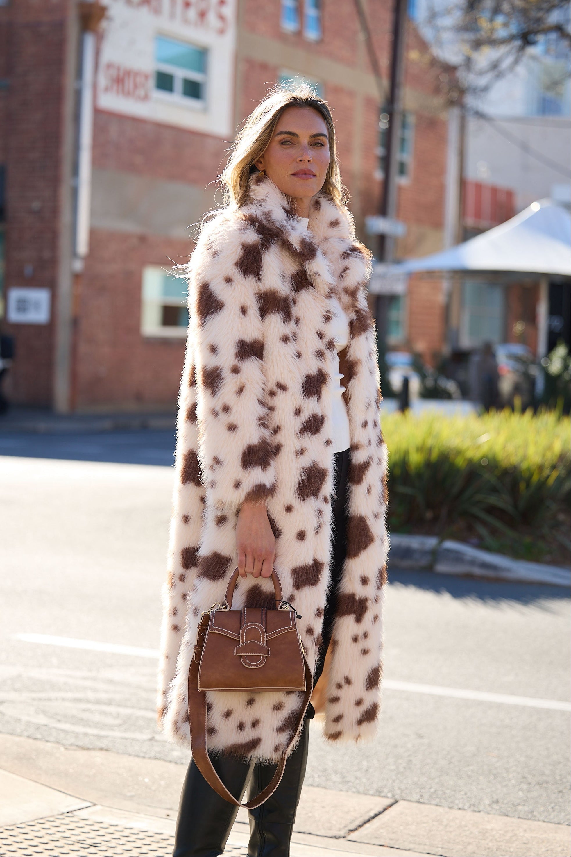 Woman wearing a long, patterned coat on a city street.