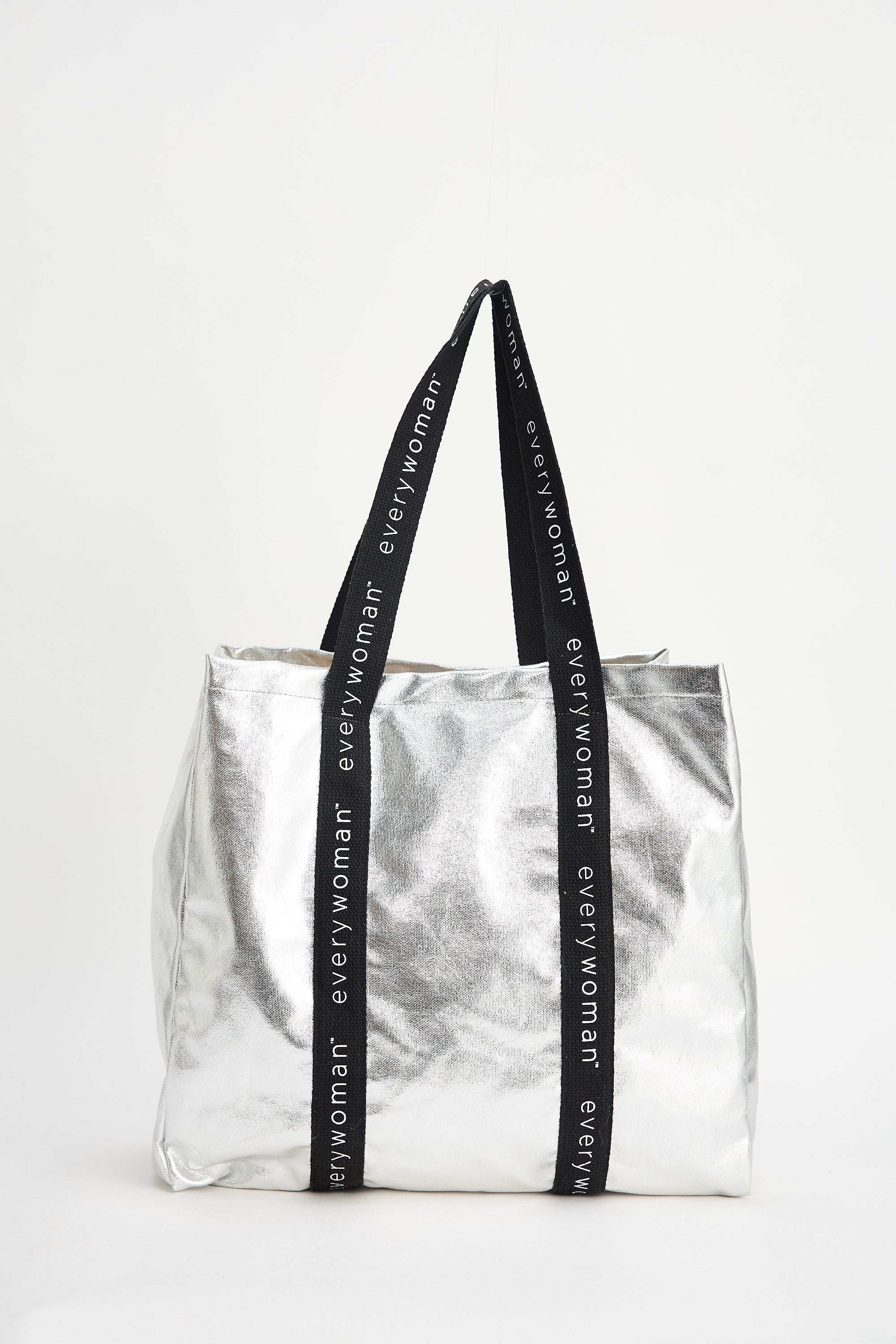 Silver tote bag with black straps featuring 'everywoman' on a white background