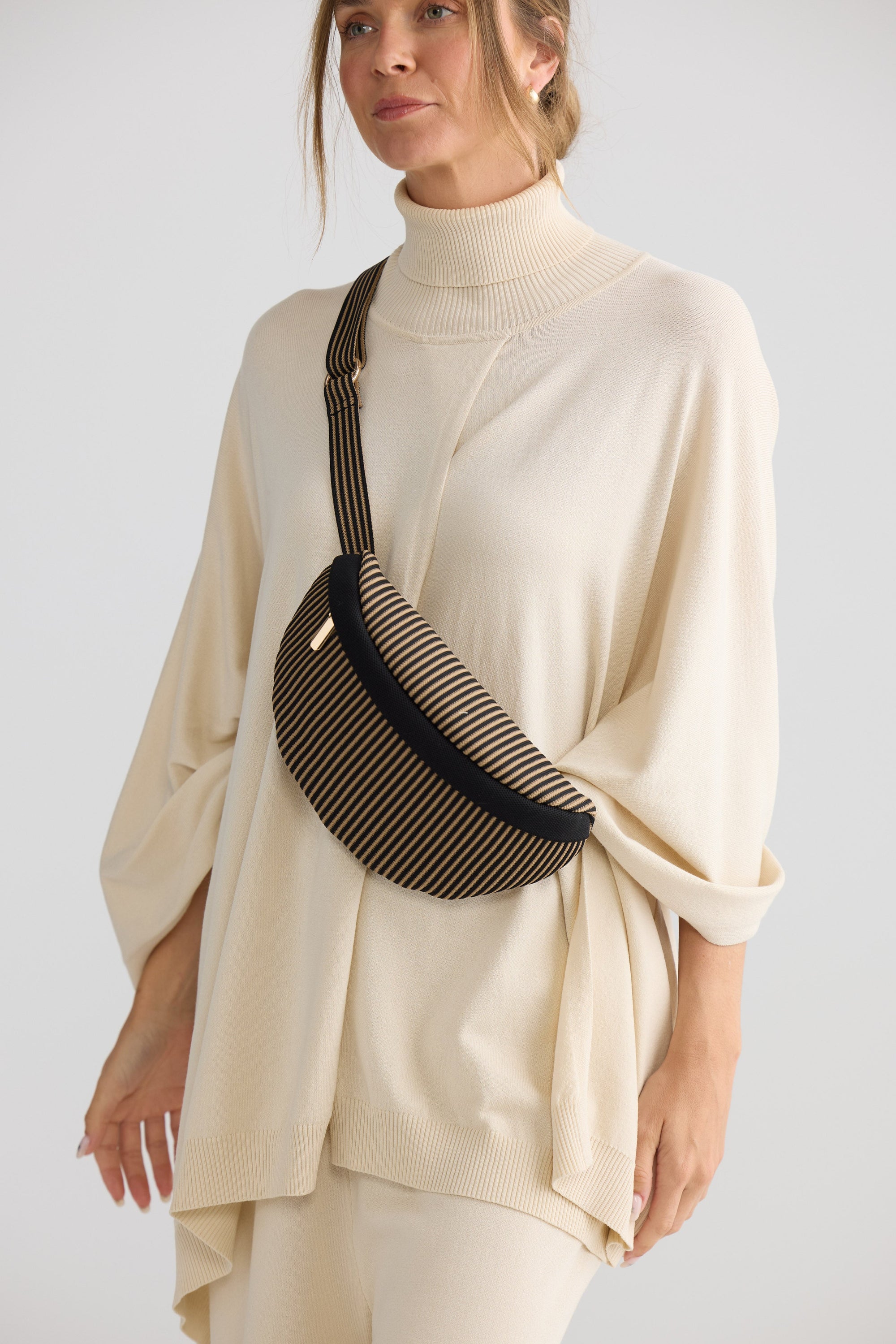 Delphi Bumbag - Black bum bag in black with stripe detailing, styled view.