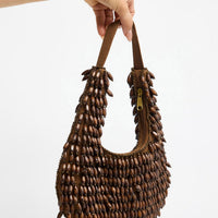 Half-moon shaped beaded clutch bag in chocolate brown and cream tones with a diamond lattice pattern, floral bead accents and gold-tone chain strap, shown hanging against a white background