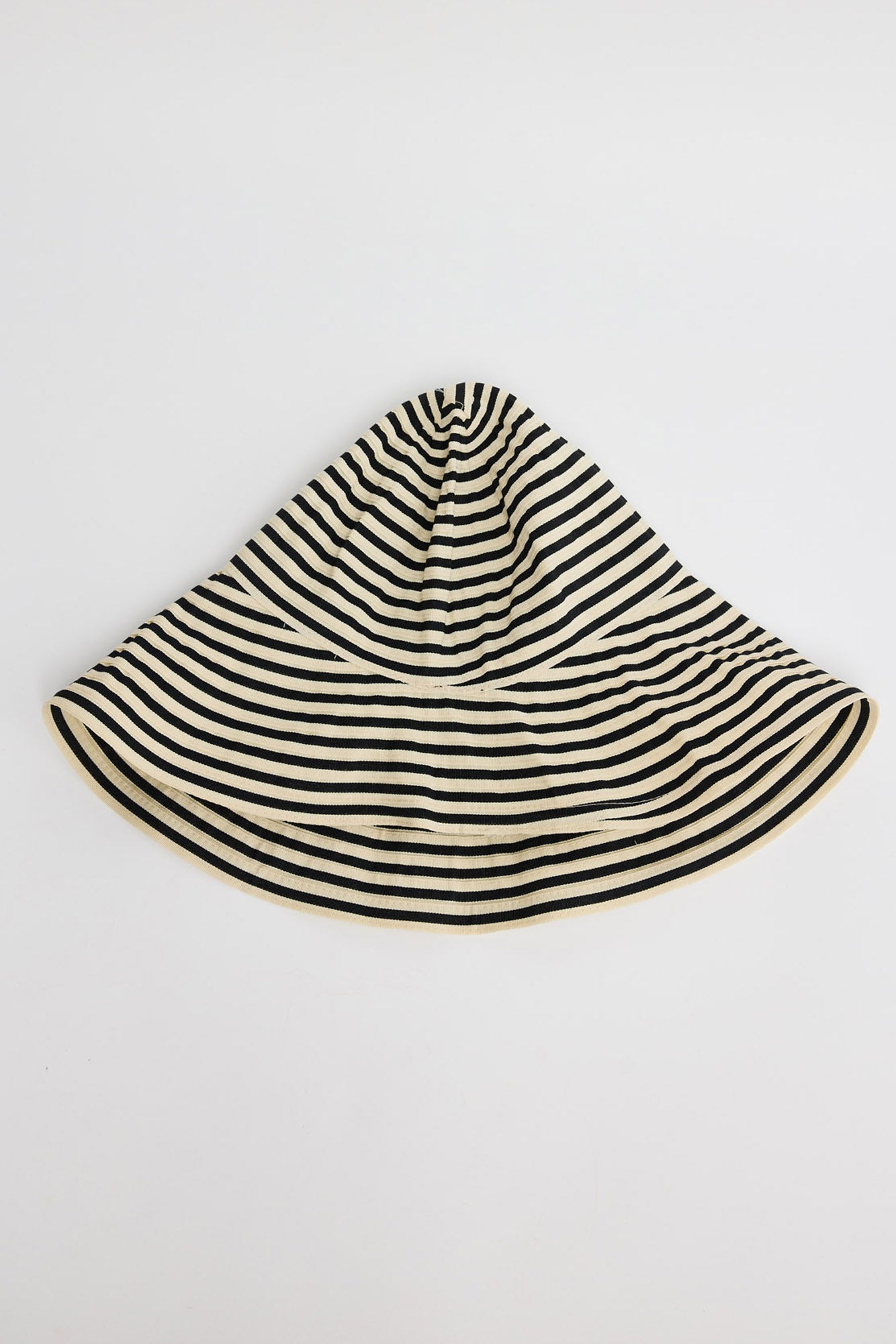 Wide-brim bucket hat in cream and black horizontal stripes with a soft unstructured crown, shown flat on a white background
