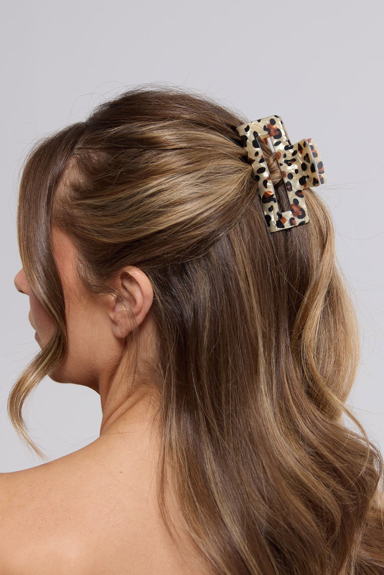 Woman wearing the Zali Hair Claw in cheetah print in a half-up hairstyle, viewed from behind