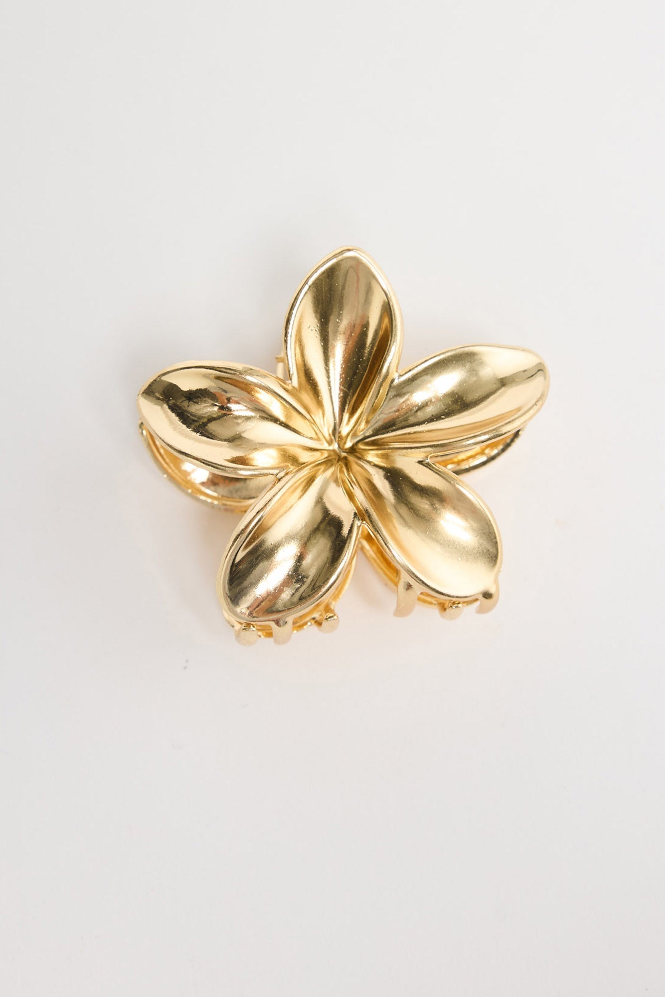 Frangi Hair Claw in gold - flat lay view of the plumeria flower-shaped metal hair claw