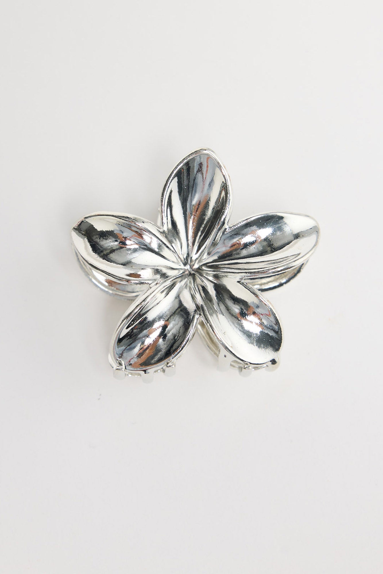 Frangi Hair Claw in silver - flat lay view of the plumeria flower-shaped metal hair claw