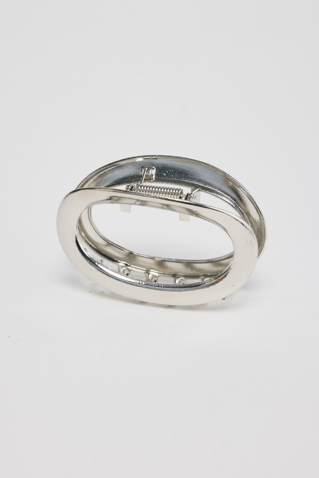 Noosa Hair Claw in silver - angled view of the sleek oval metal hair claw showing the spring hinge